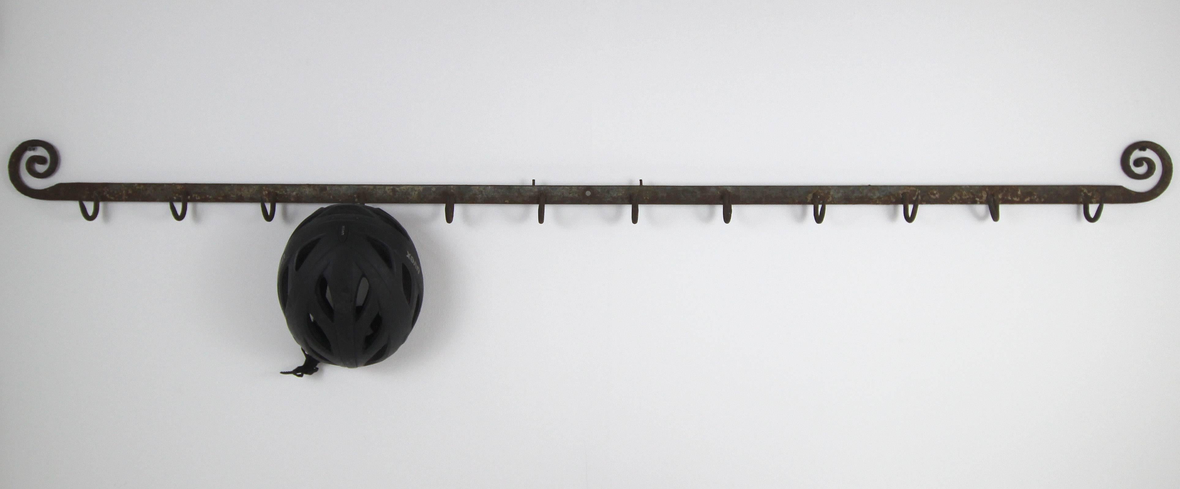 Six-foot long wrought iron rack of 12 hooks with curlicue ends; American, 19th century.