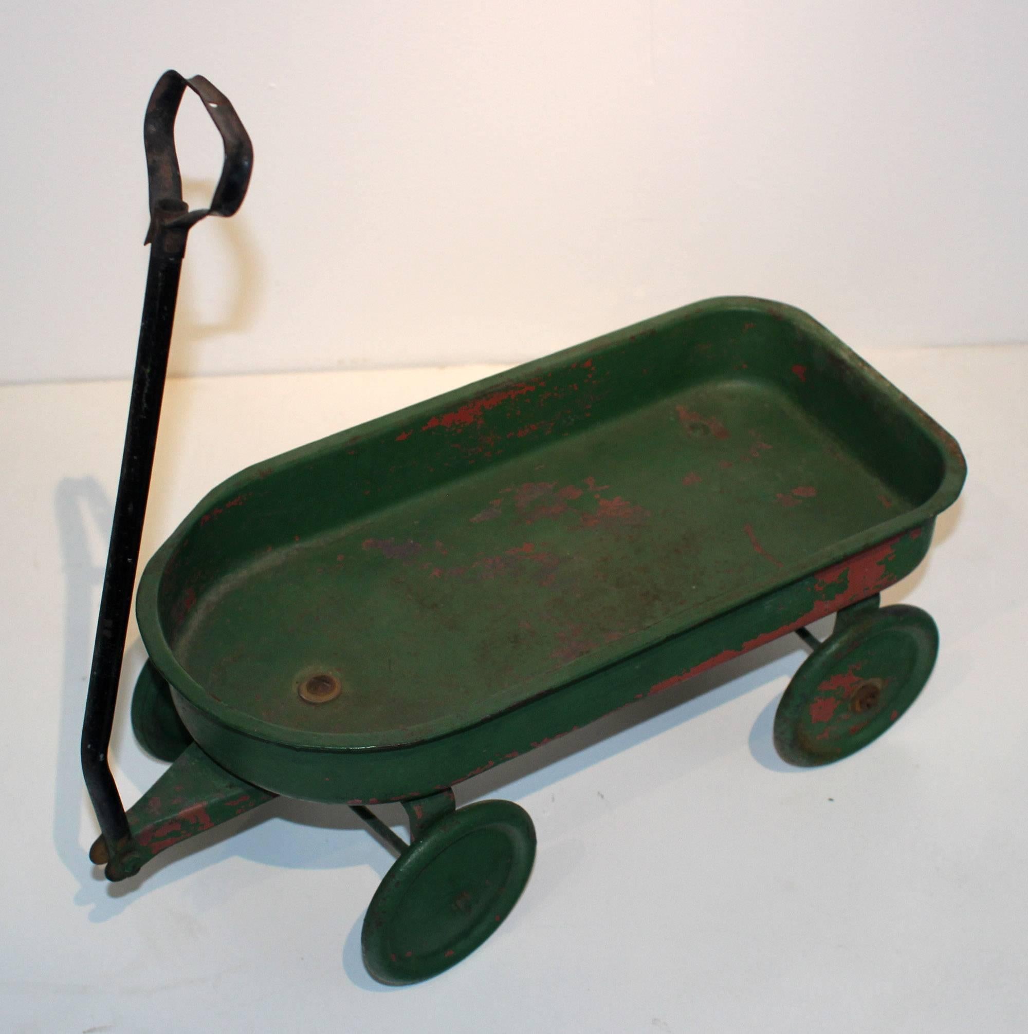 Cute little metal wagon painted in old green over red paint. American, early to mid-20th century. The noted measurements are for the body of the wagon; the handle is 15