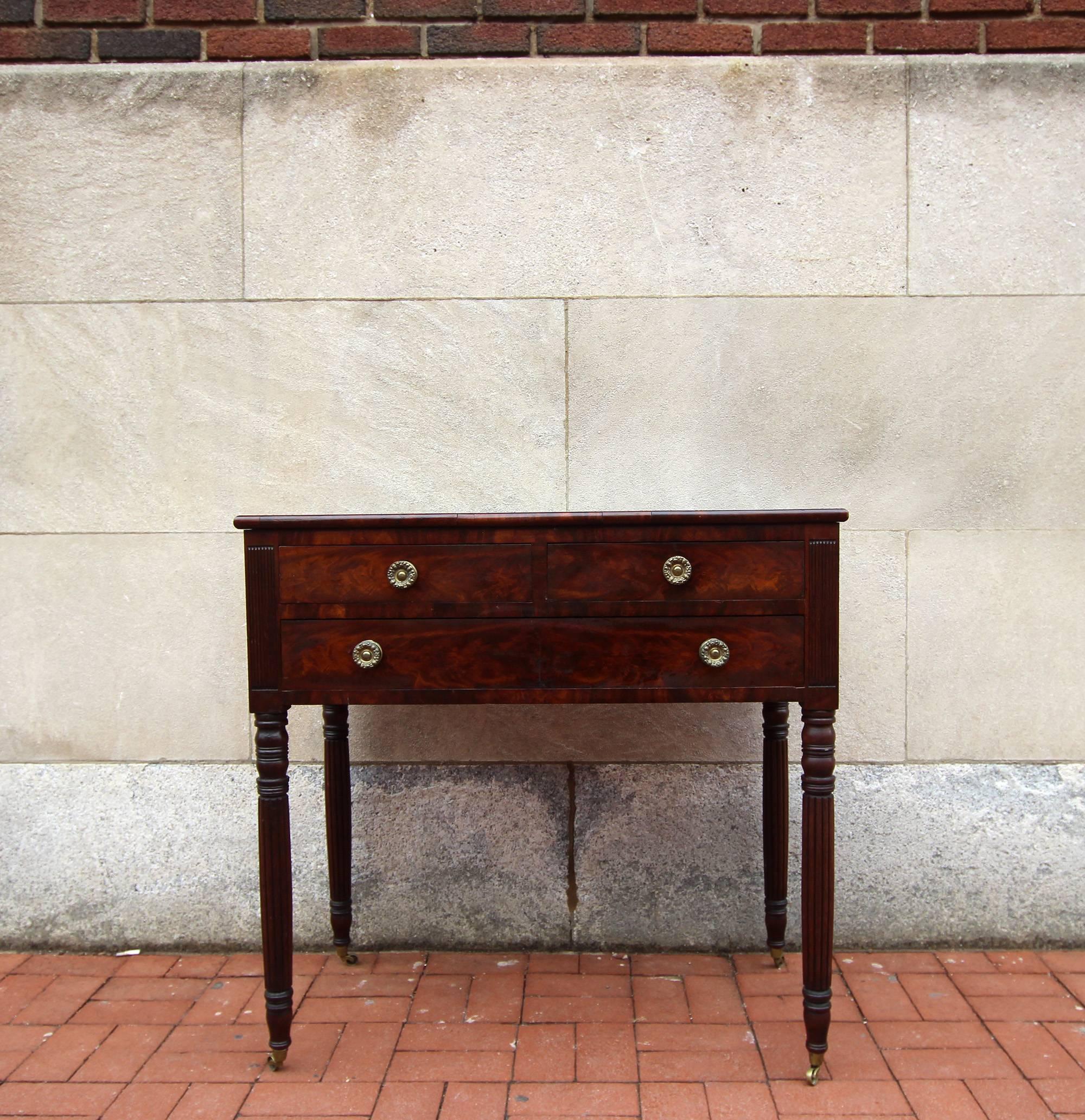 Handsome, excellent quality, Federal mahogany server with original pressed brass rosette drawer knobs and original solid brass casters, dovetail construction, turned and reeded legs and good figuring to the mahogany throughout. Good three drawer
