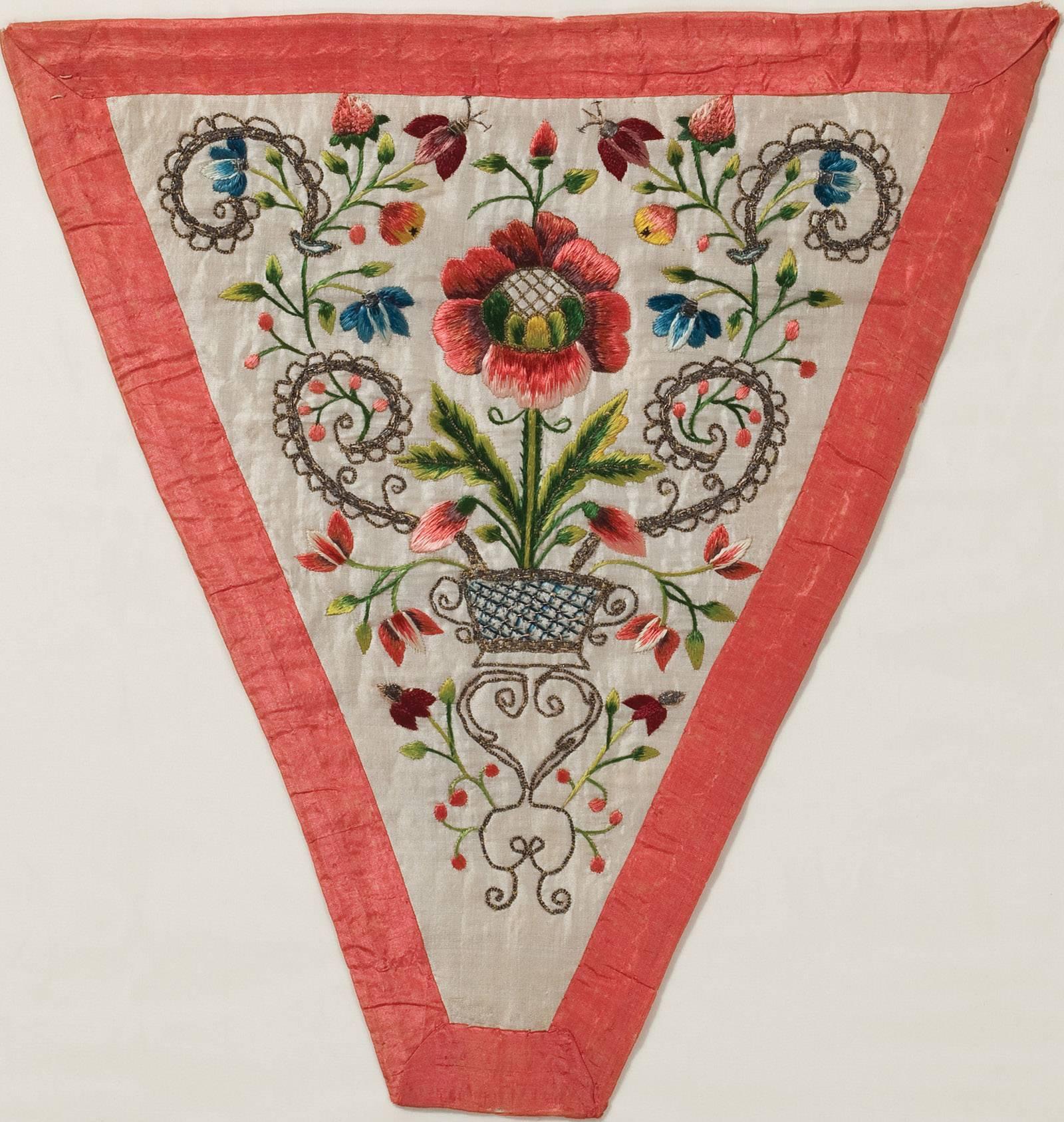 In the mid-18th century, fashionable American and European ladies made and wore these pieces, which were called stomachers decorative V-shaped fabric panels that formed the center portion of the bodice of a gown, emphasizing the cone shape desired