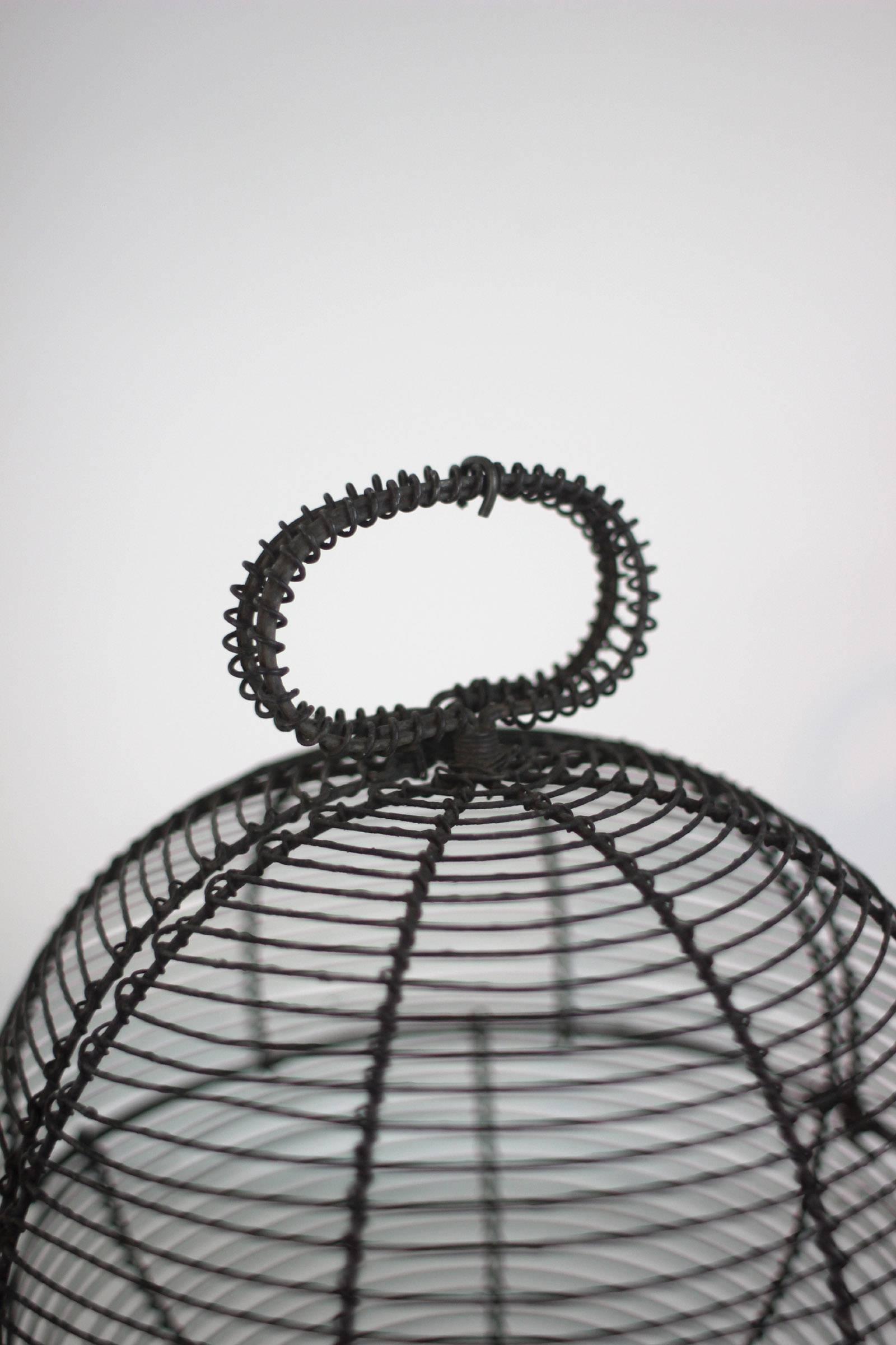 This unusual and well-made handsome footed basket is globular when closed and swivels open to half that form. Made of tightly twisted wire, it's very sturdy.