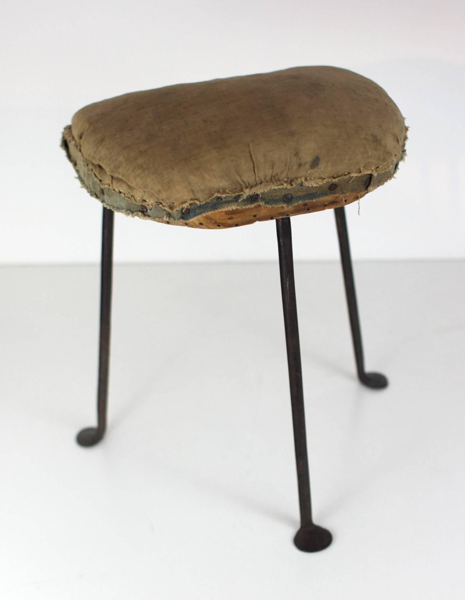 Exceptional tripod stool, upholstered over wood, with fine wrought iron legs that end in penny-shaped feet, all original; American, circa 1820.