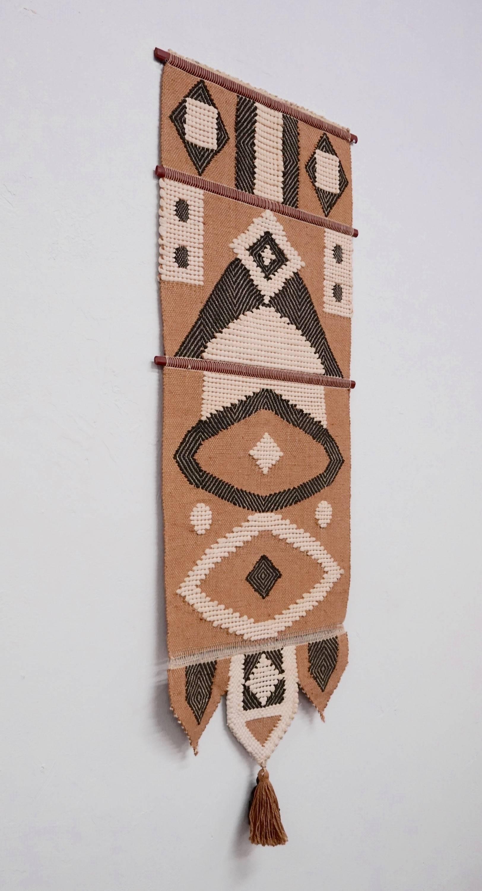 Woven wool geometric tapestry supported with wooden rods.