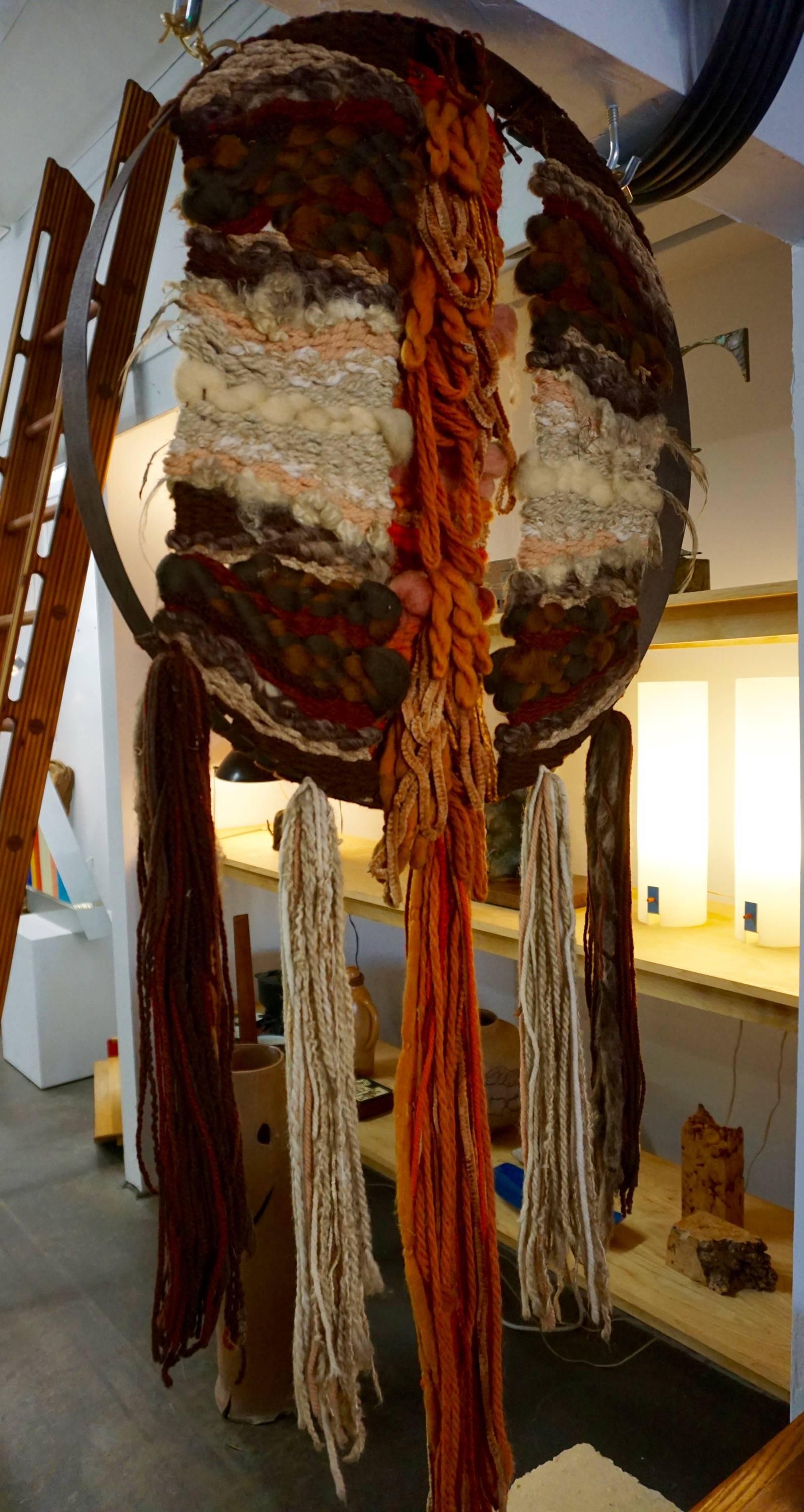 Unusual colorful weaving framed in a metal ring with hanging wool tassels.