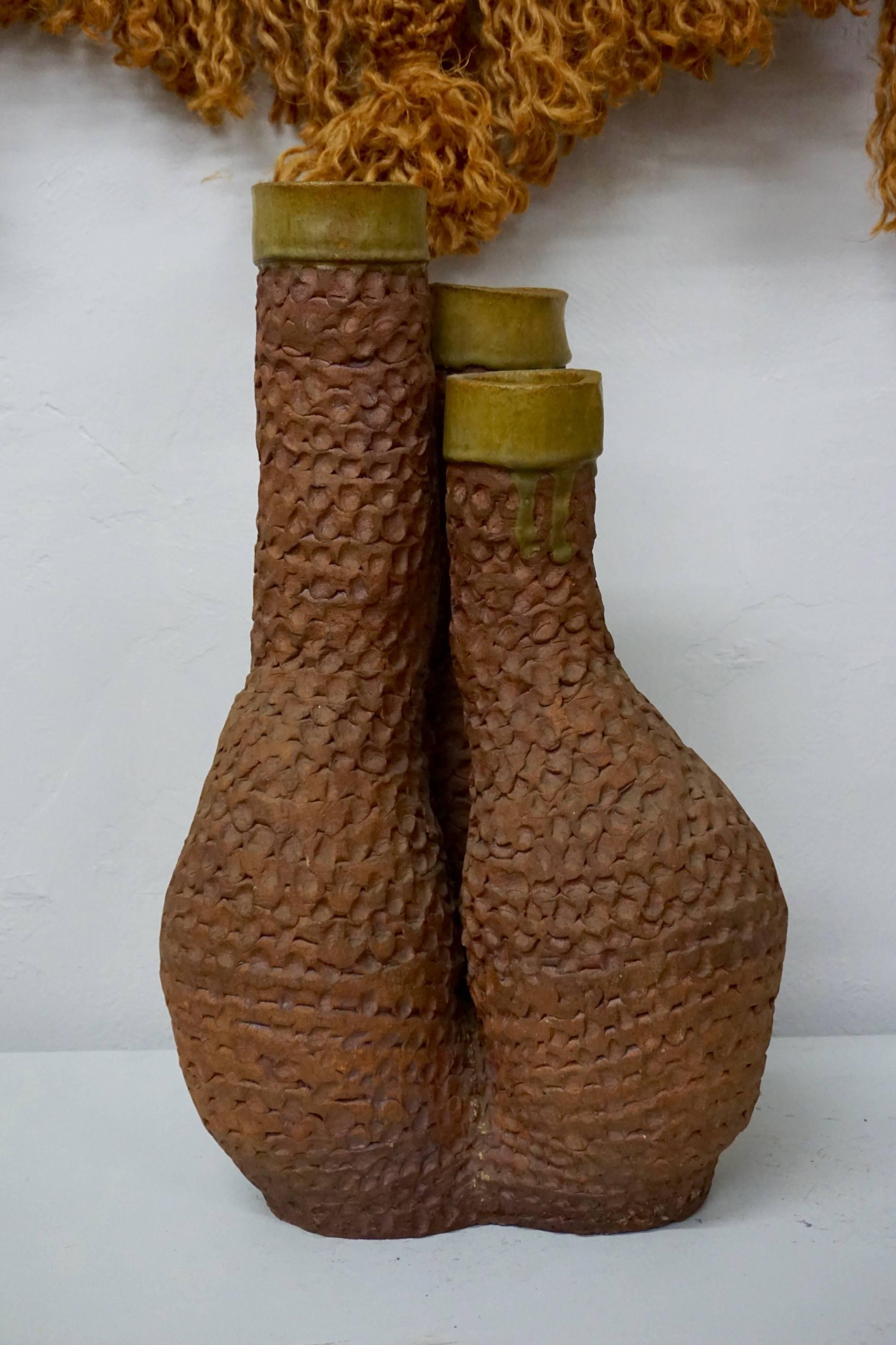 Coiled clay vessel with finger pinched texture and three glazed tops.