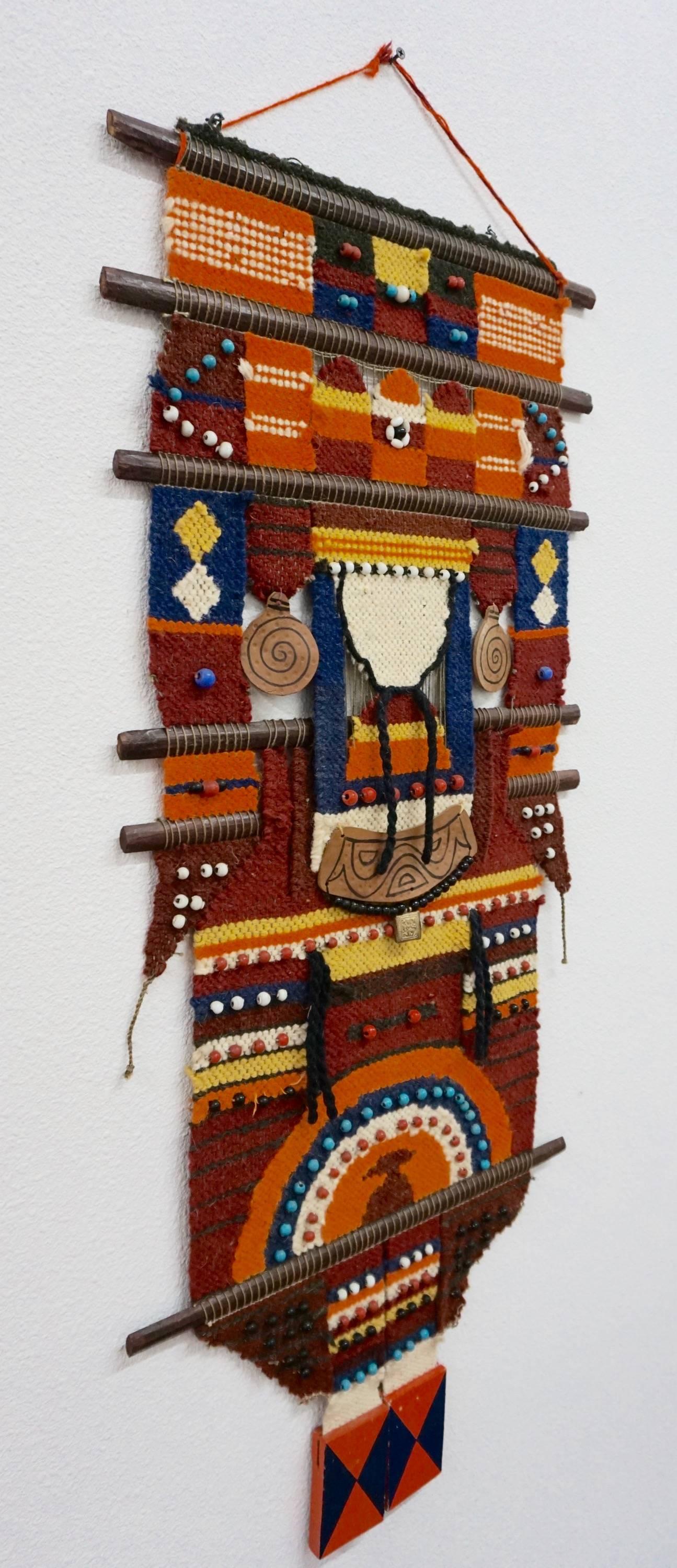 This fascinating flat weaved wall hanging has leather, shells and beads incorporated into the fabric and two painted wood blocks dangling from the bottom.