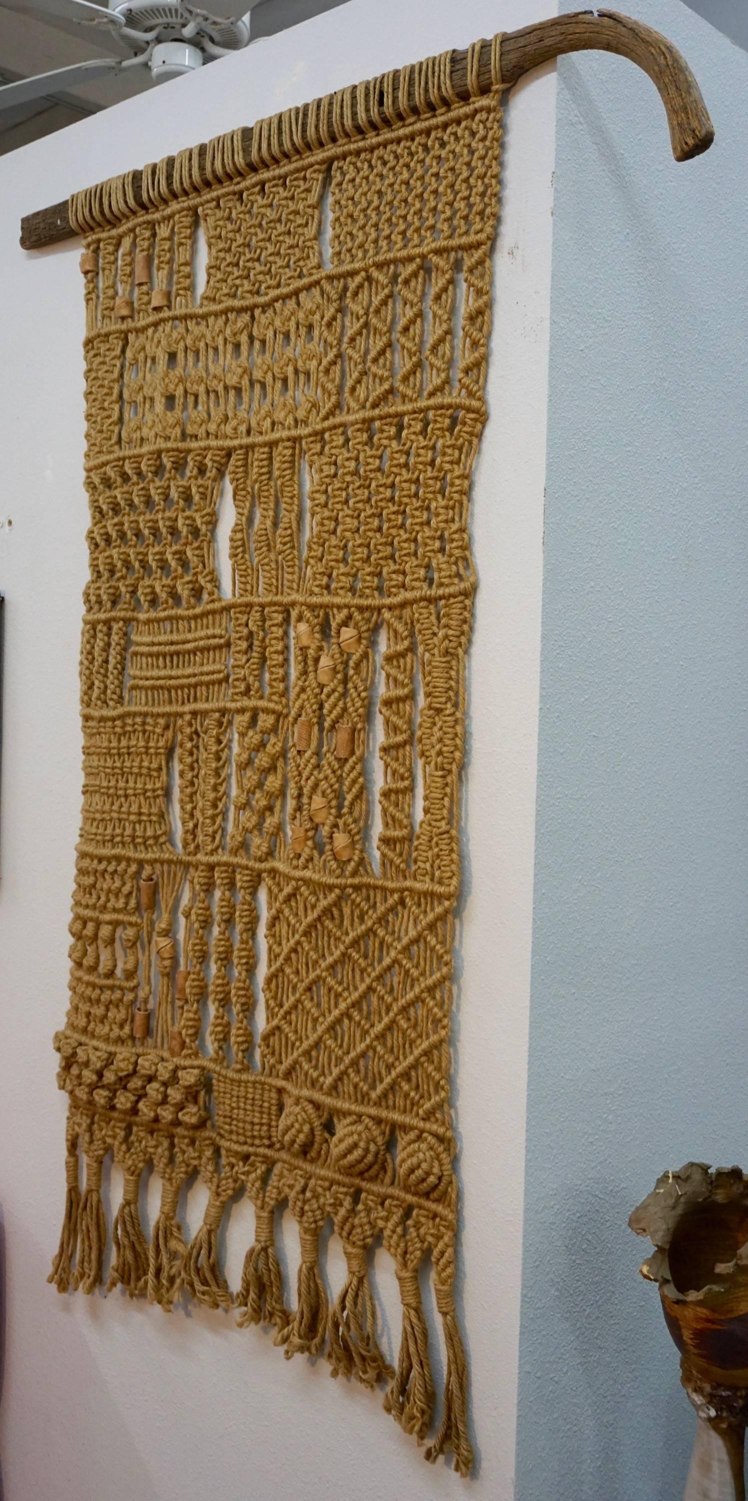 Wall hanging hemp/jute macrame mounted on a weathered plow handle with incorporated ceramic beads.