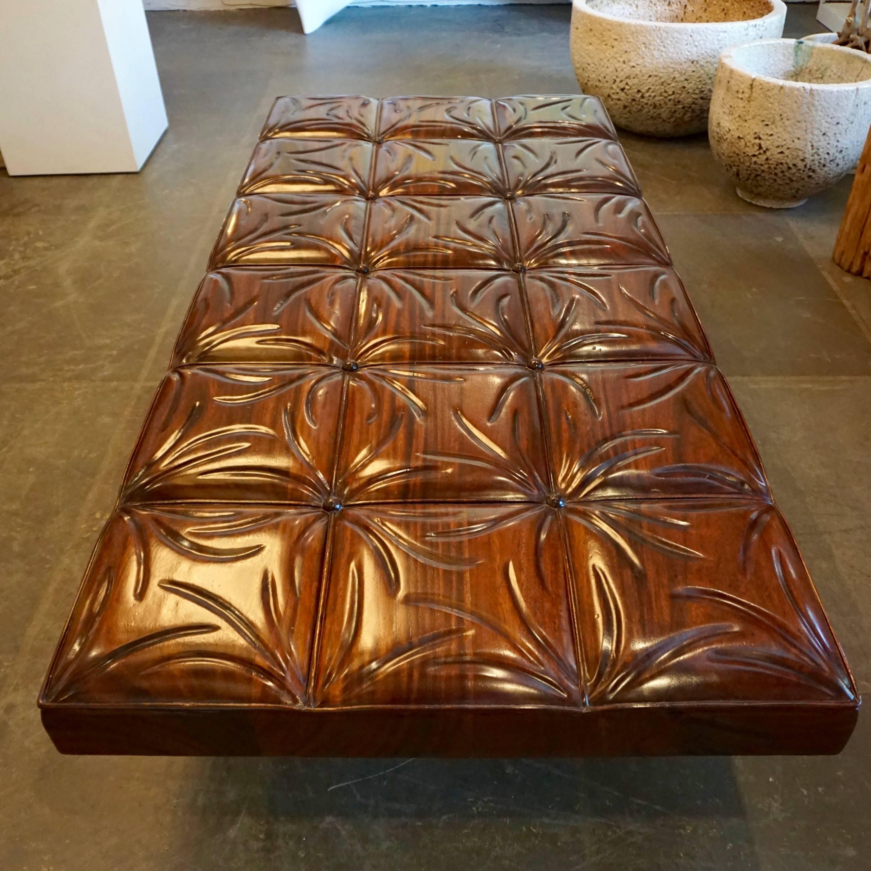 Carved from solid mahogany resembling a tufted leather bench including the buttons. Mounted on square chromed steel legs.