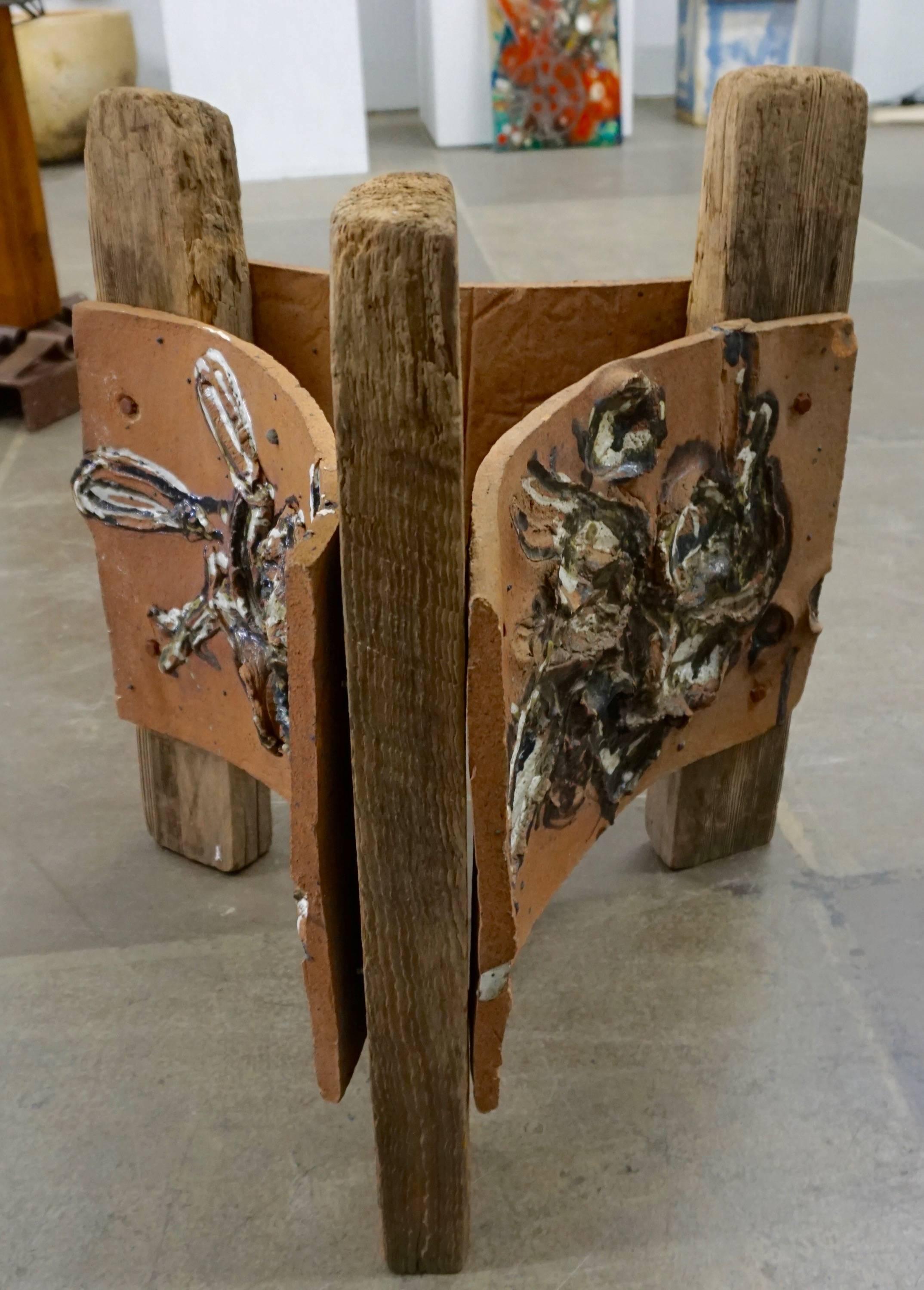 Three stoneware slabs mounted on old lumber with glazed abstract images in relief. A 1" chip to one of the slabs where it is mounted to the lumber. Unsigned.