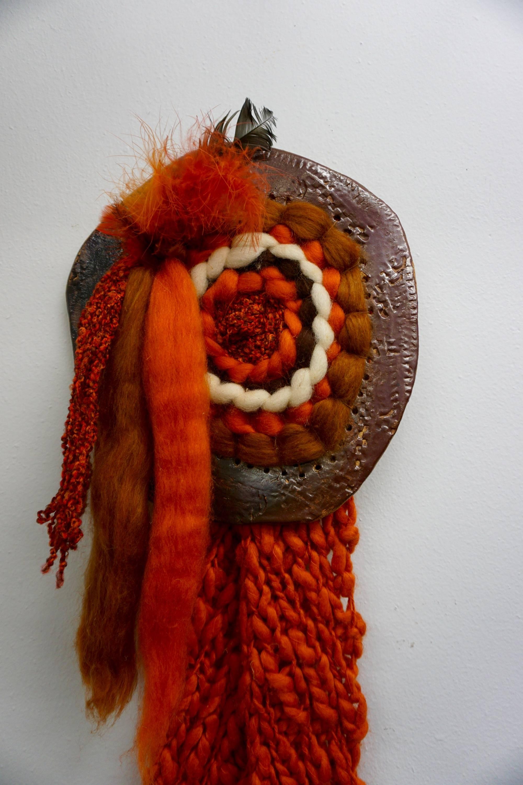 Organic weaving mounted on a hand thrown ceramic disc. Bright orange wool, tufted wool and feathers.