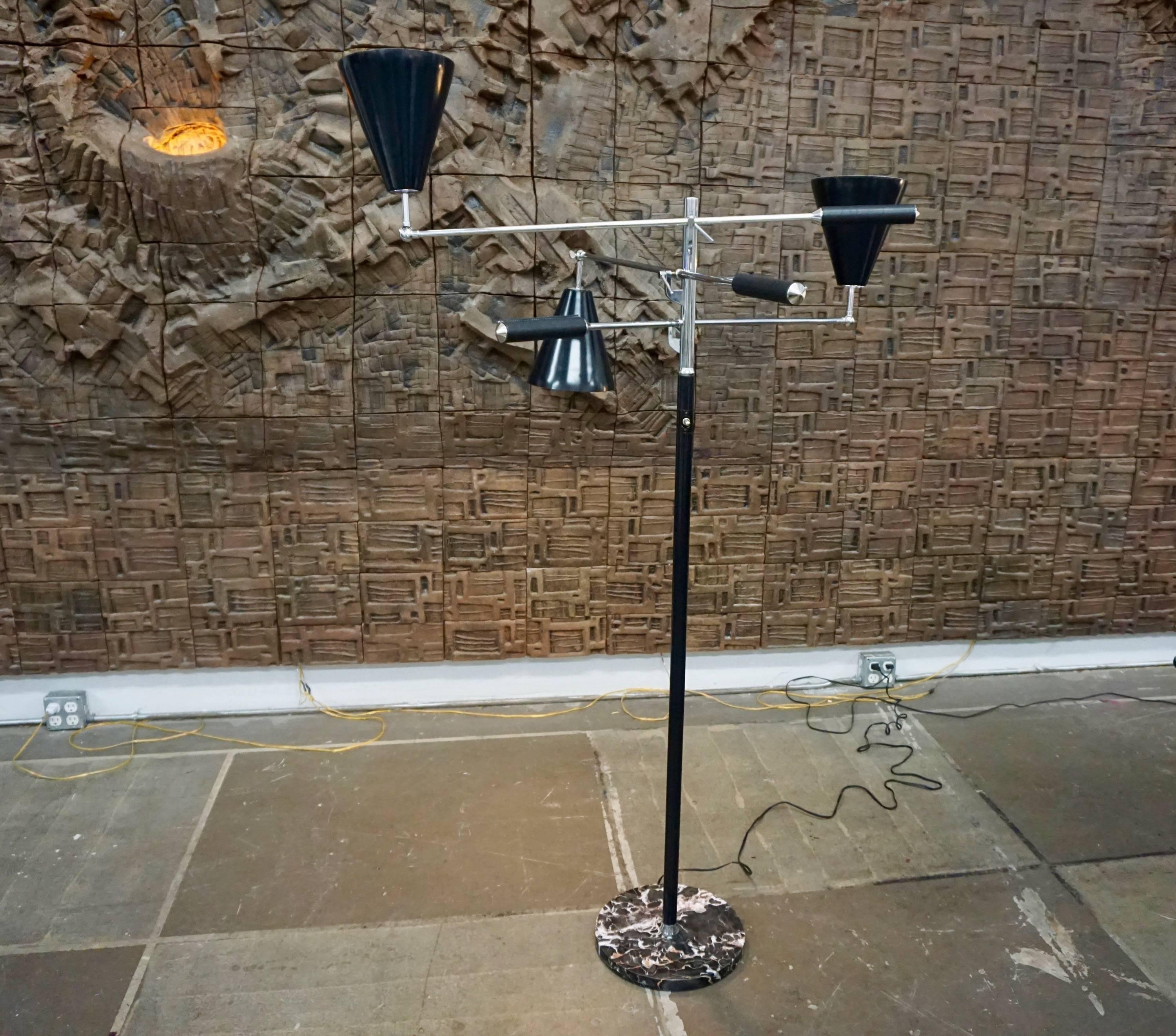 Sculptural three-armed floor lamp in the style of Arredoluce, Italy. A chromed shaft and adjustable, articulating arms with stitched black leather handles and black metal shades; all seated in a round marble base. Stamped “Made in Italy“ at the top