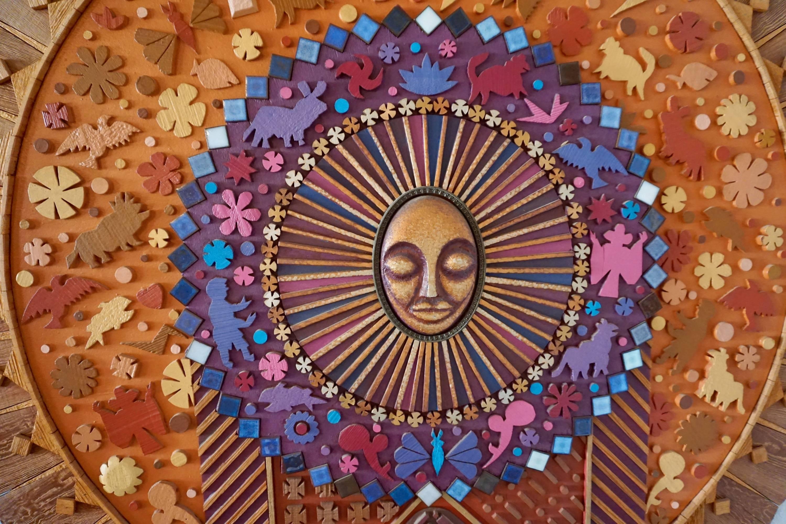 Large 1970s wood construction by San Diego artist, Dennis Davis. Sunburst centre radiating with wood cut-outs of flowers, animals and ceramic tiles.