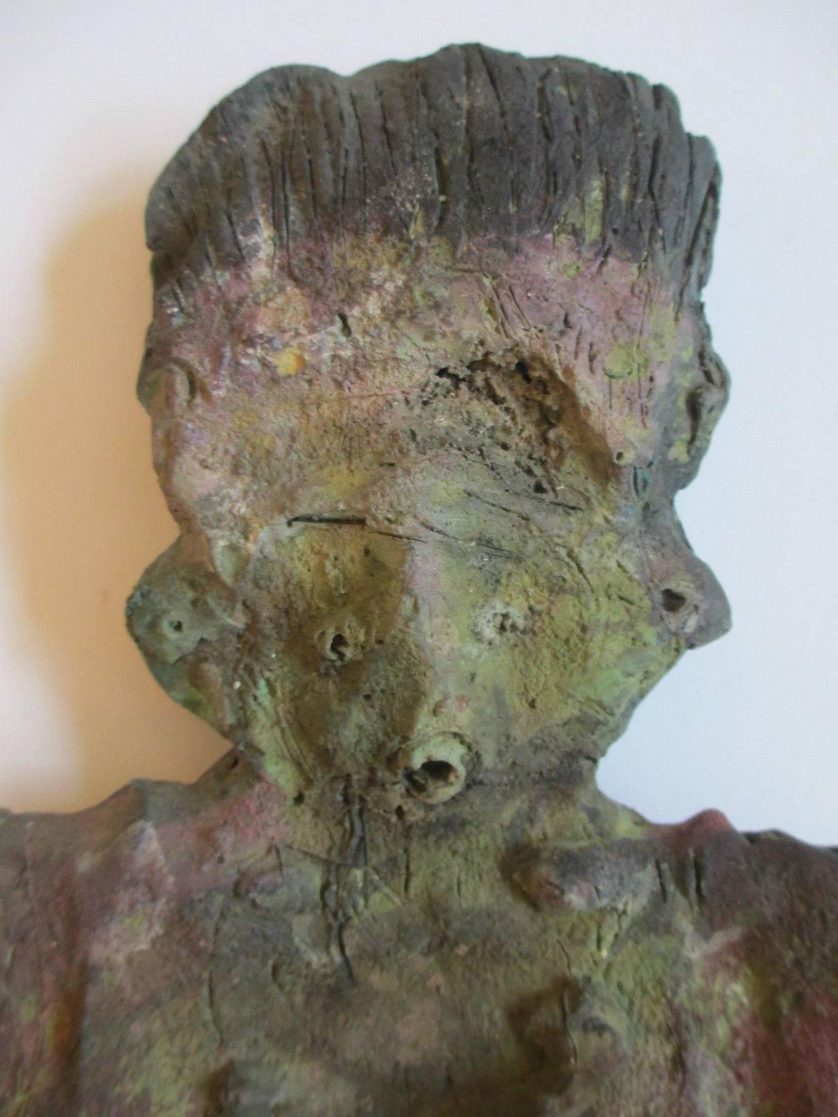 This bronze expressionist figure has the look of an ancient relic.  Created in solid bronze, the sculpture has a unique patina with an overall verde green color, it also has areas of pale magenta.  It  is mounted on a wood pedestal for a more
