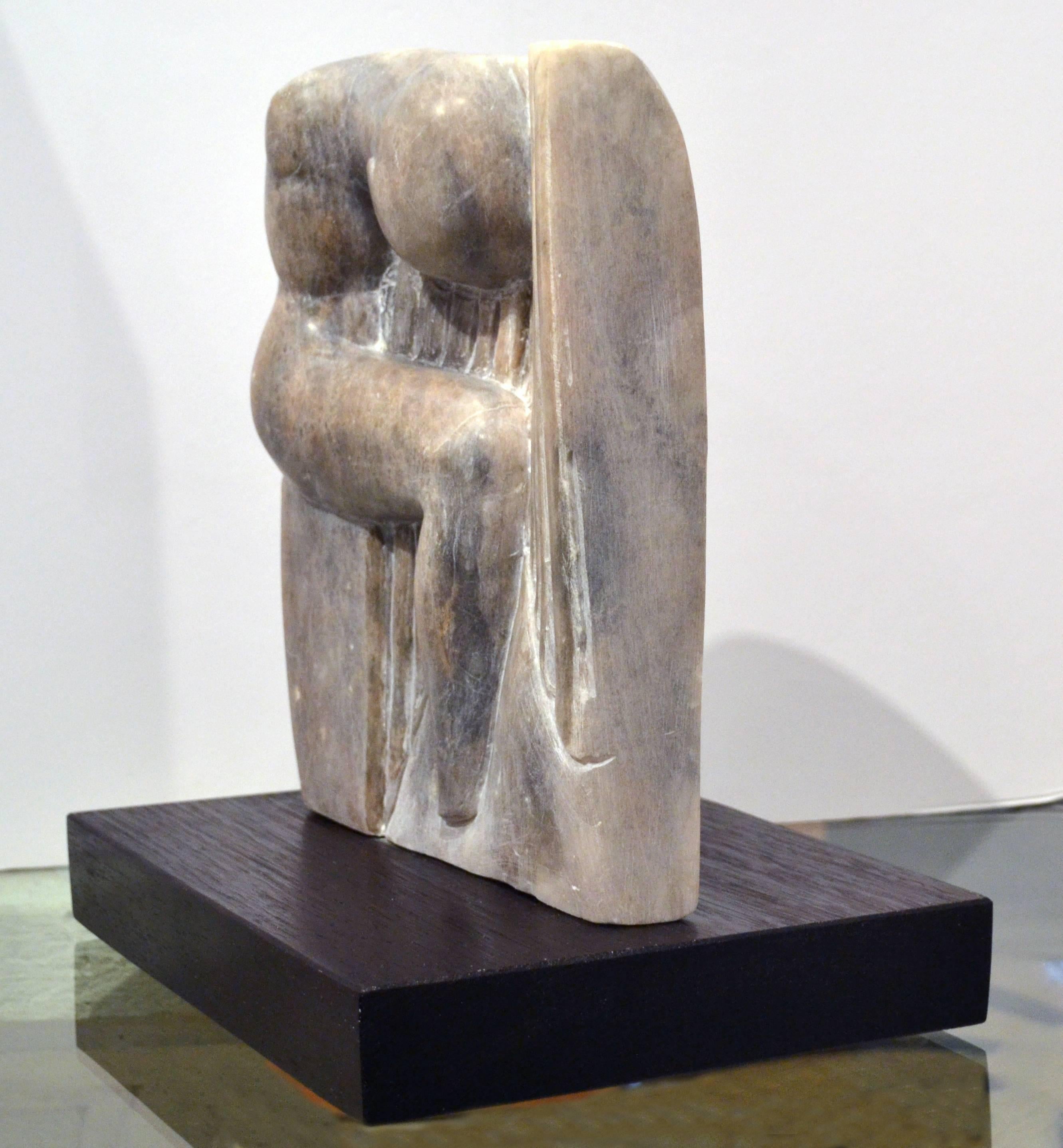 California artist Scott Donadio (b. 1961) hand-carved this abstract alabaster (mineral that is rather translucent) sculpture, it is signed at the base. The sculpture features a seated figure against a carved alabaster background. It is an elegant
