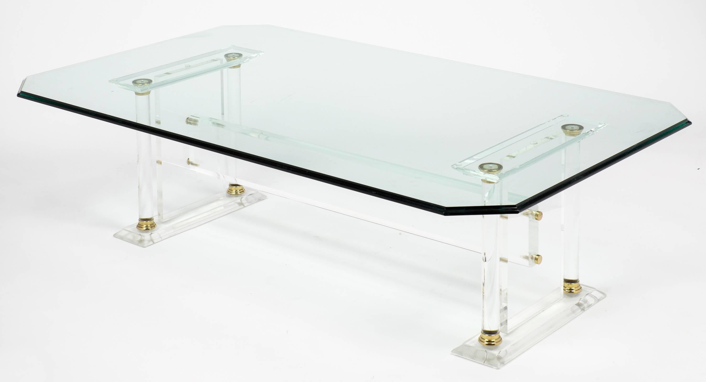 A sleek, crisp French Mid-Century Modern Glass Top Lucite Coffee Table with brass trim that creates the illusion of space with all of the amenities. This spectacular translucent piece with a classical appeal has a clipped corner glass slab tabletop
