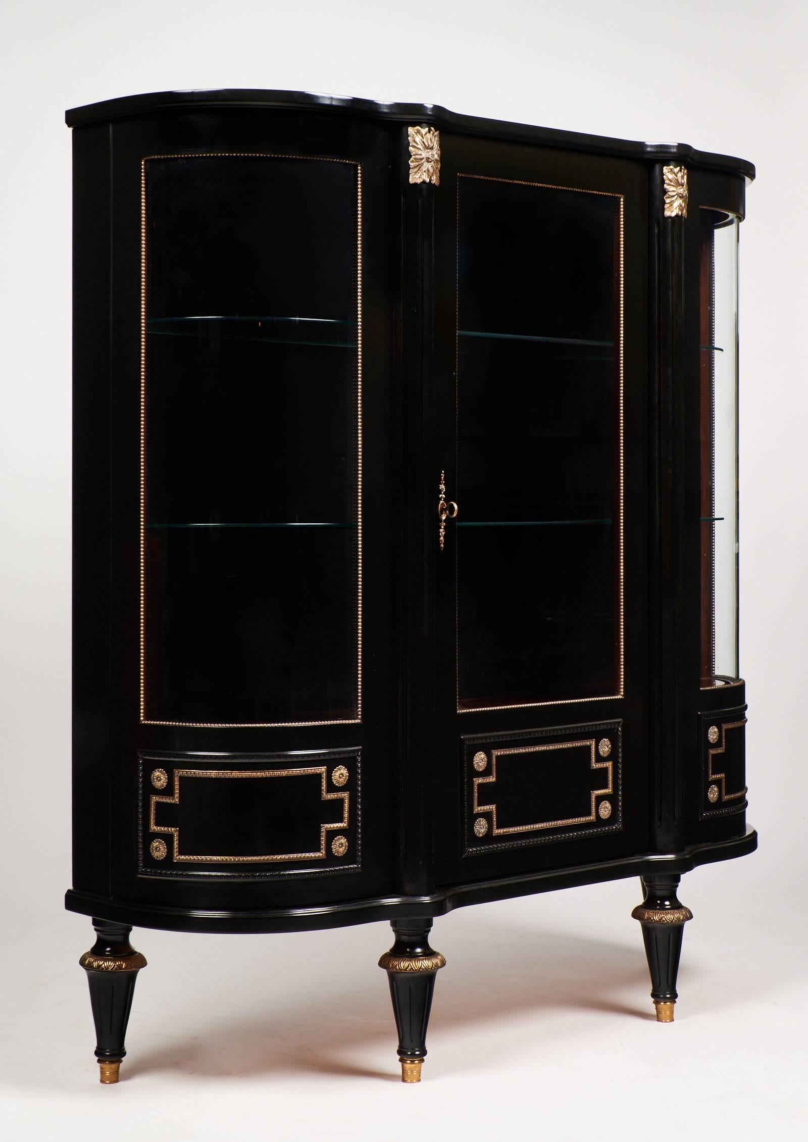 Mahogany vitrine ebonized with a lustrous French polish. All original glass doors, curved sides and shelves with all original hardware.