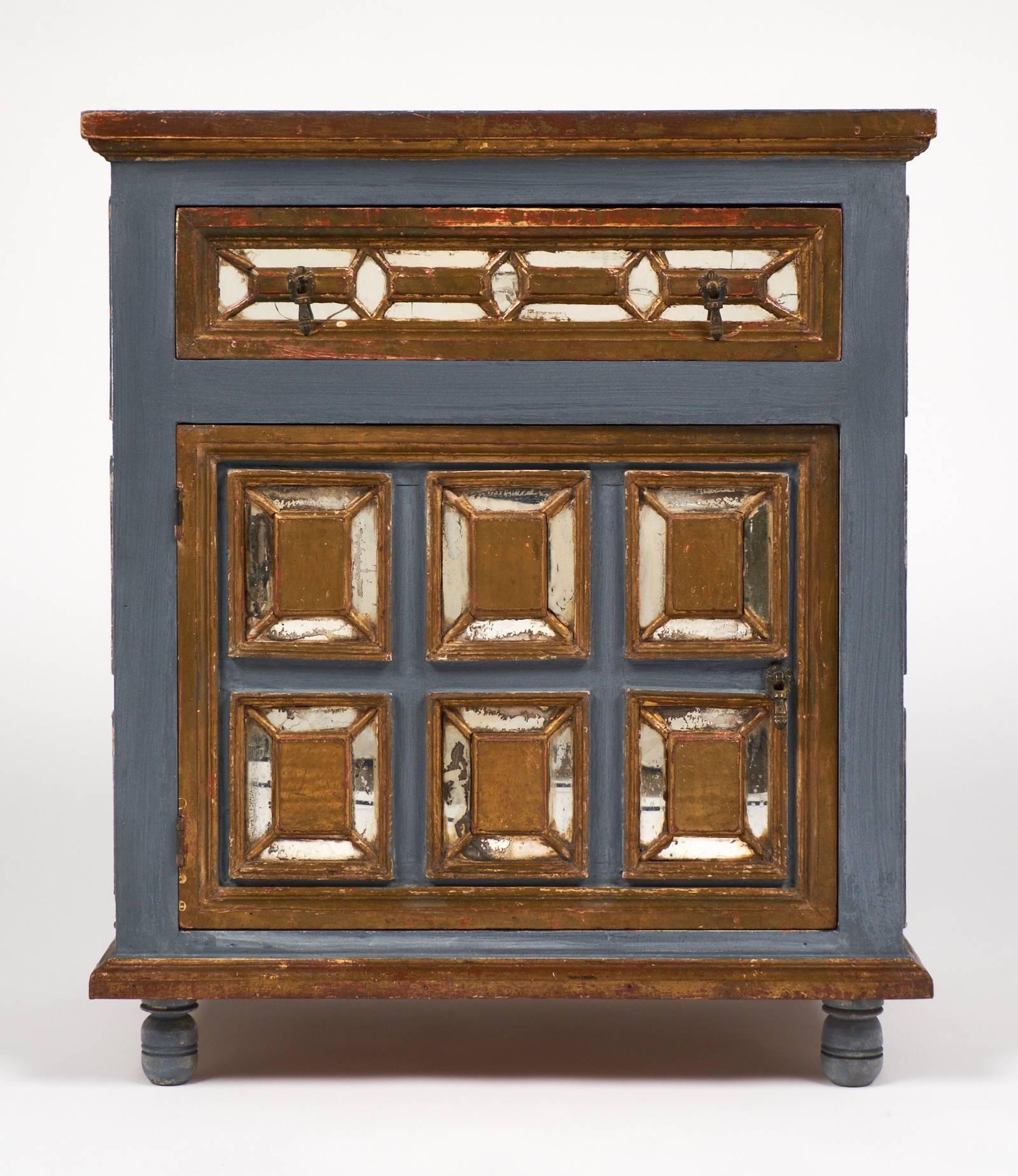 Antique Italian cabinet from Venice with one drawer and one door, original hardware, painted and finished with a sienna undertone gold leaf with mirrors inlaid in the moldings.
A coordinating piece is also available.
