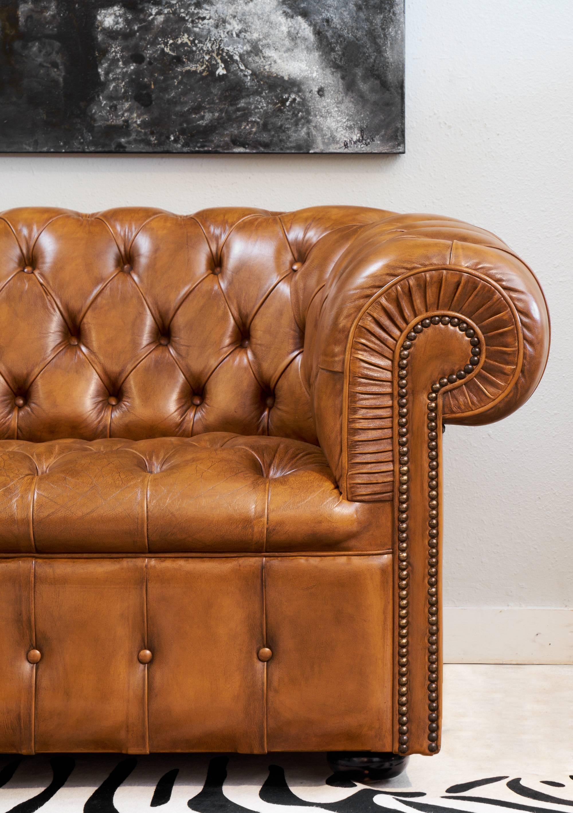 English vintage Chesterfield sofa in a gorgeous tufted cognac leather with bronze nail heads and ebonized bun feet. Great patina, so comfortable and elegant.