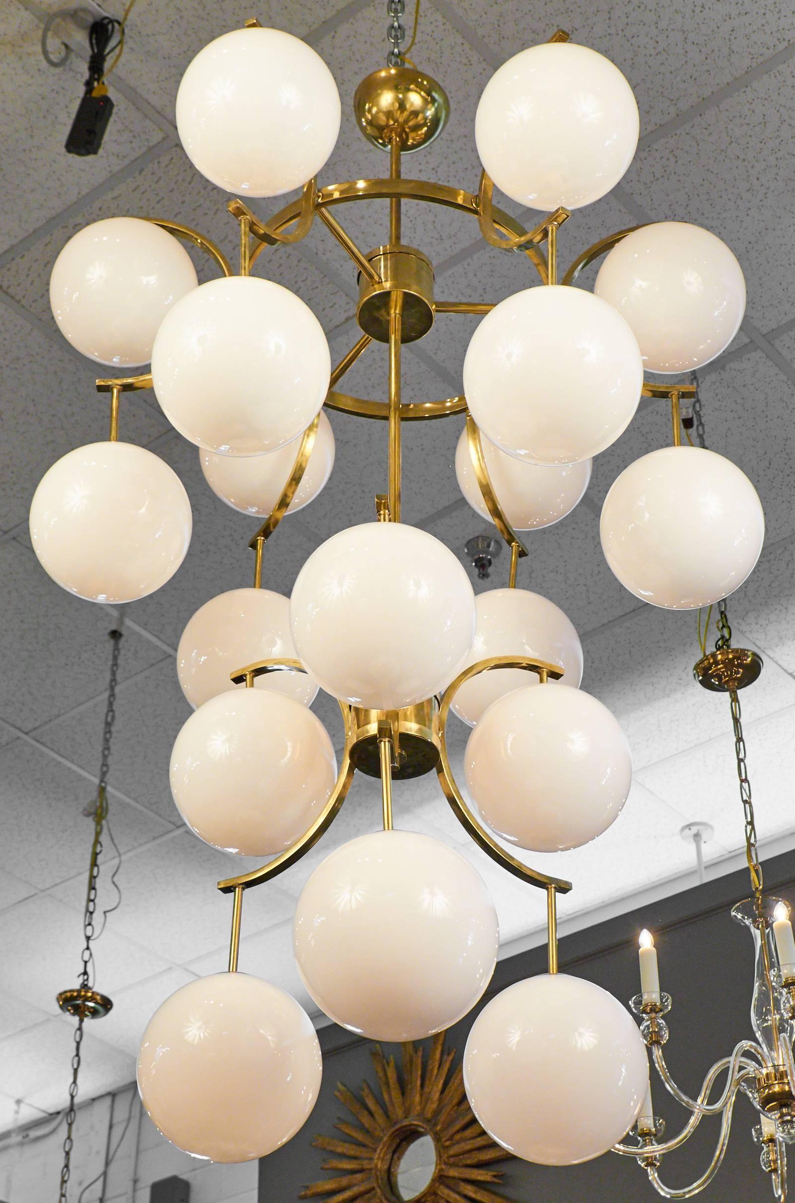 18 white Murano glass globes Cascade down a Mid-Century Modern style brass structure on this wondrous chandelier. Rewired for the US to hold 18 medium-base light bulbs.

This fixture is currently located at our dealer's warehouse in Italy. Please
