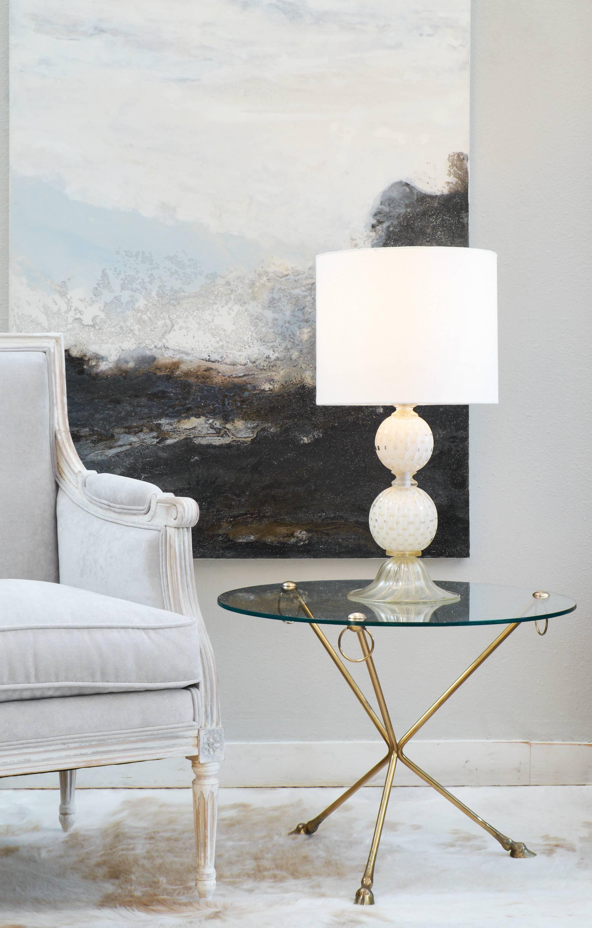 French vintage round glass topped side table. Unique brass tripod base features hanging rings and hoof feet. Classic style and excellent size for an occasional table.