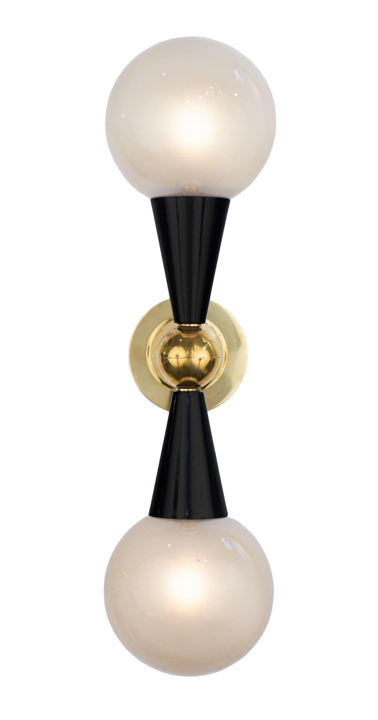Murano glass globe shades and black lacquered cones extend from a brass structure on each of these Italian Mid-Century Modern style sconces. A matching chandelier is also available. In the manner of Stilnovo. Wired to fit US standards.
