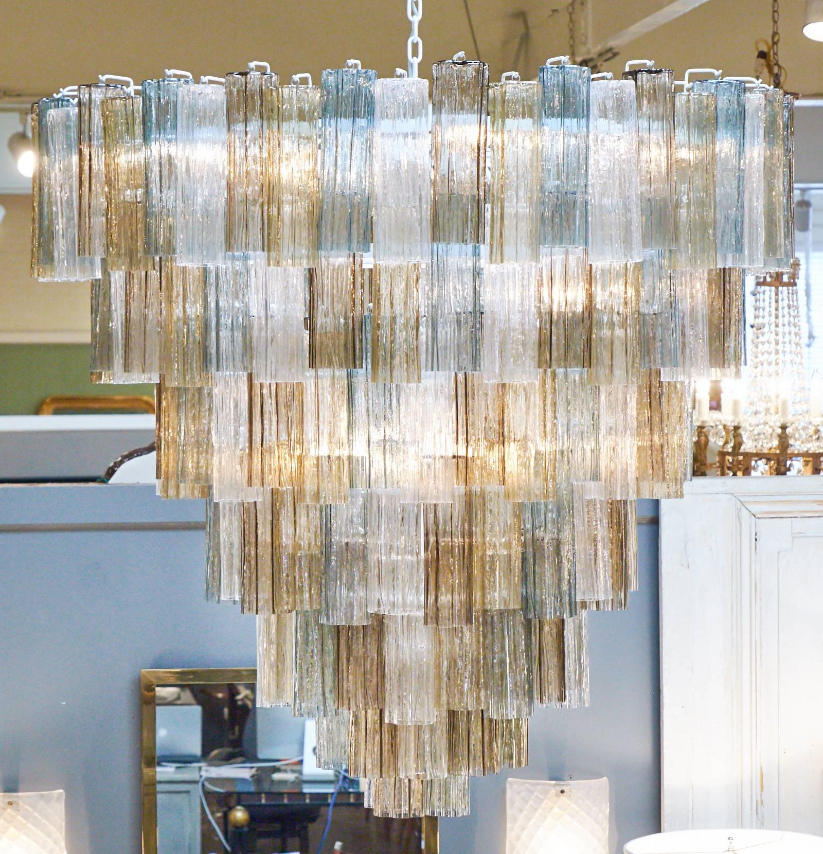 Italian Murano glass chandelier in the style of Mazzega with seven tiers of glass hanging on a white coated steel structure, rewired for the US. Extruded, textured glass in light and dark amber, teal and crystal clear Murano glass, creating a