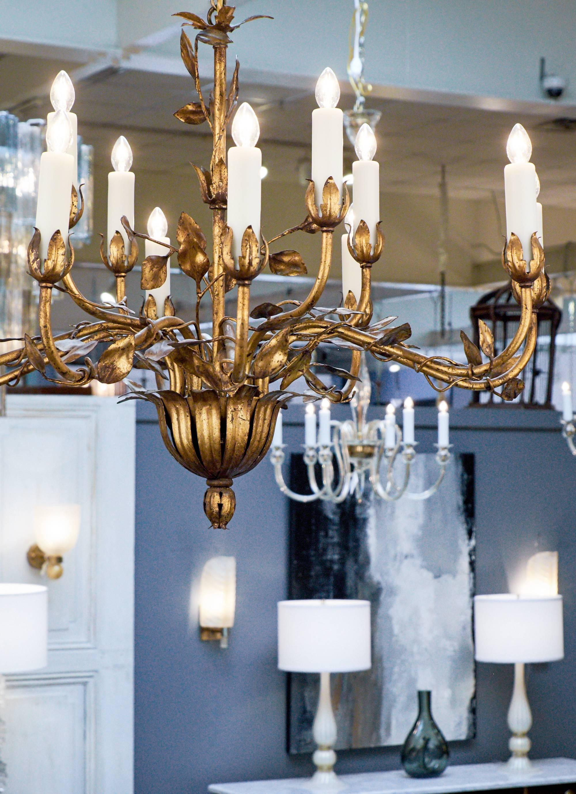 Vintage hand-hammered tole chandelier finished with gold leaf. Two levels with a total of twelve branches with leaf bobeches, adorned with twisting stems and leaves. A refreshing light fixture with a gleaming finish.

Rewired for the US. Height