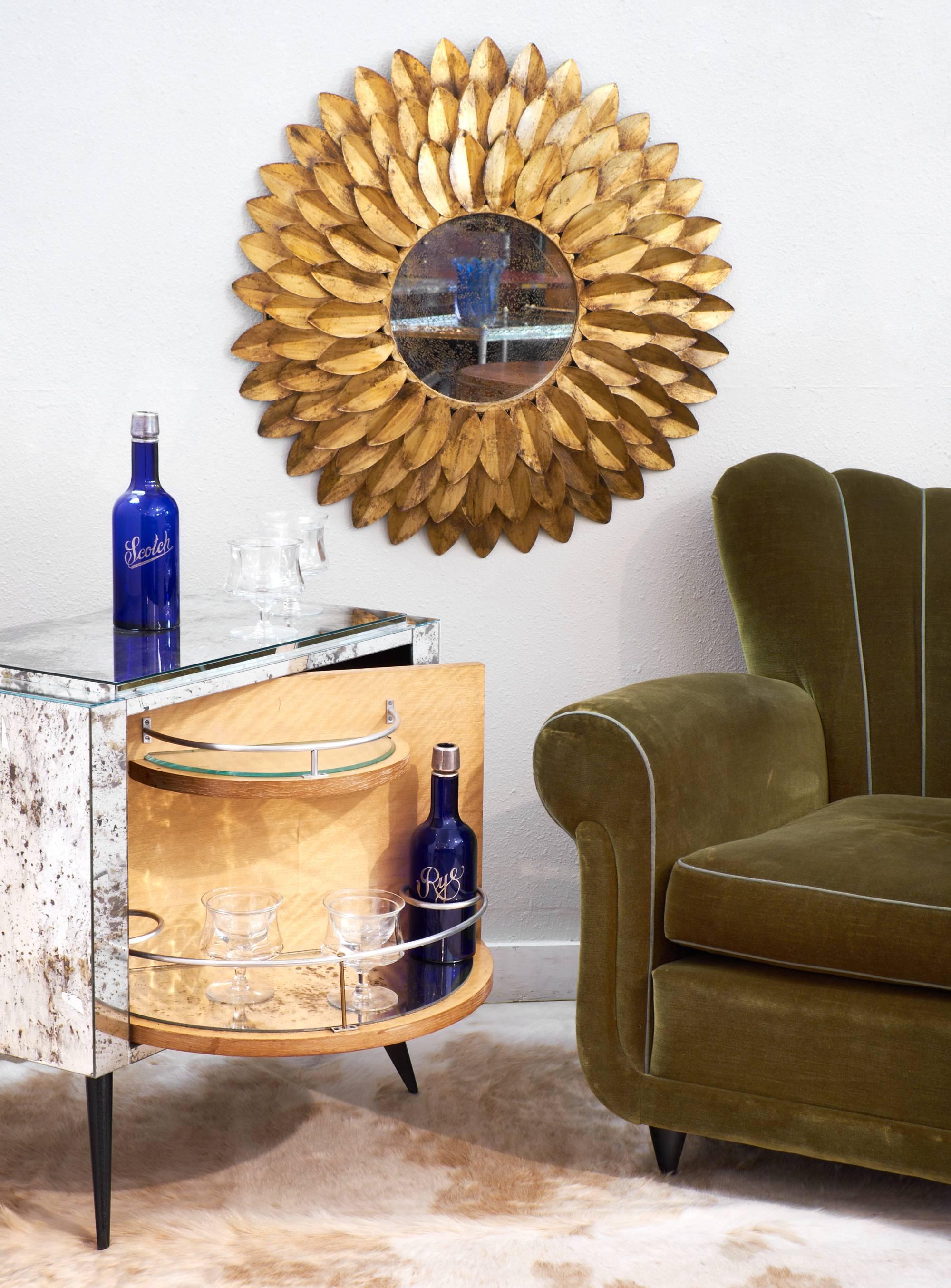 Vintage gilt metal sunburst mirror reminiscent of a sunflower with three overlapping layers of gold petals surrounding a central antiqued glass mirror.