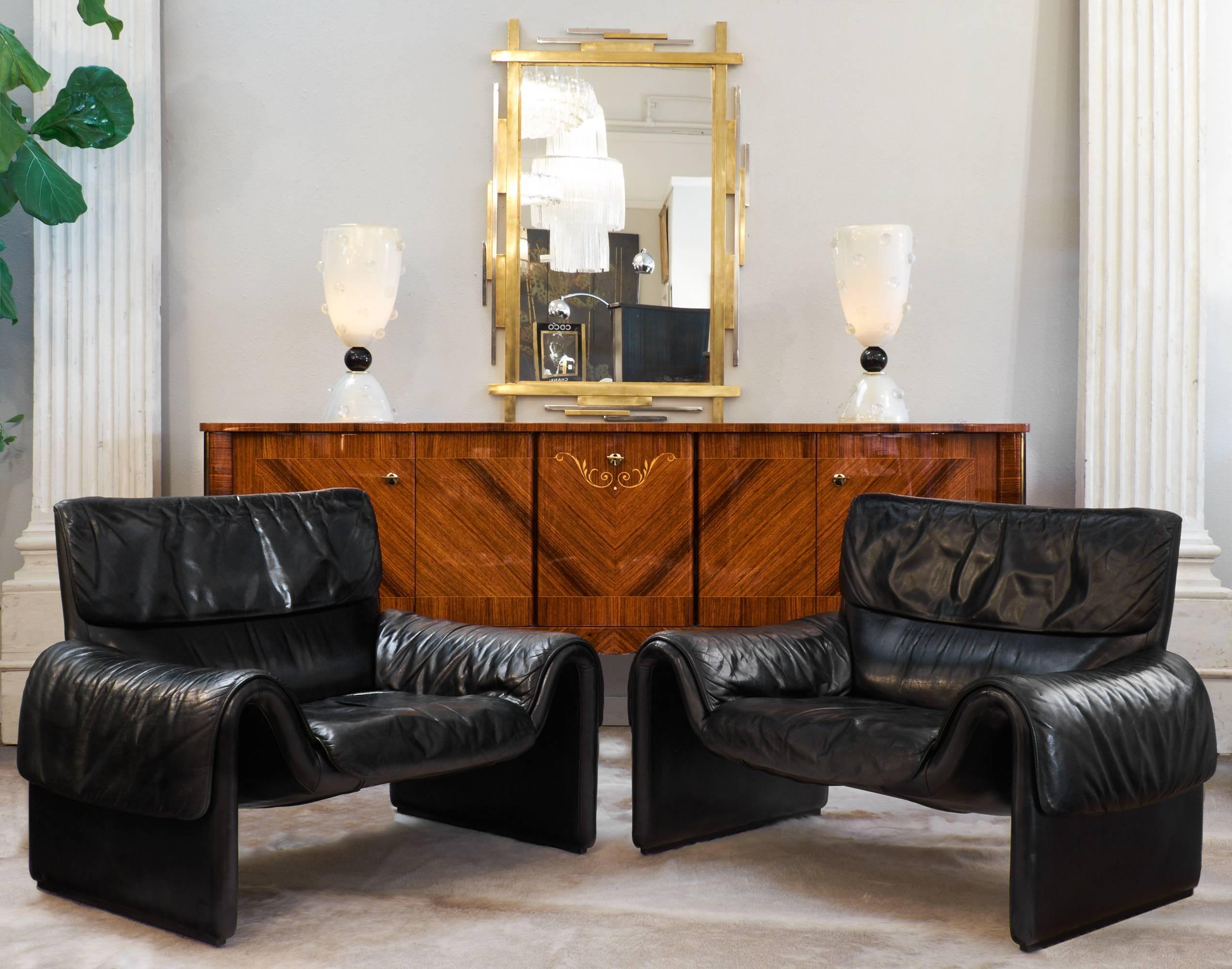 Vintage pair of black leather armchairs by De Sede, unique, beautiful front profiles, with open curving arms. Nice wide seats and comfortable backs.