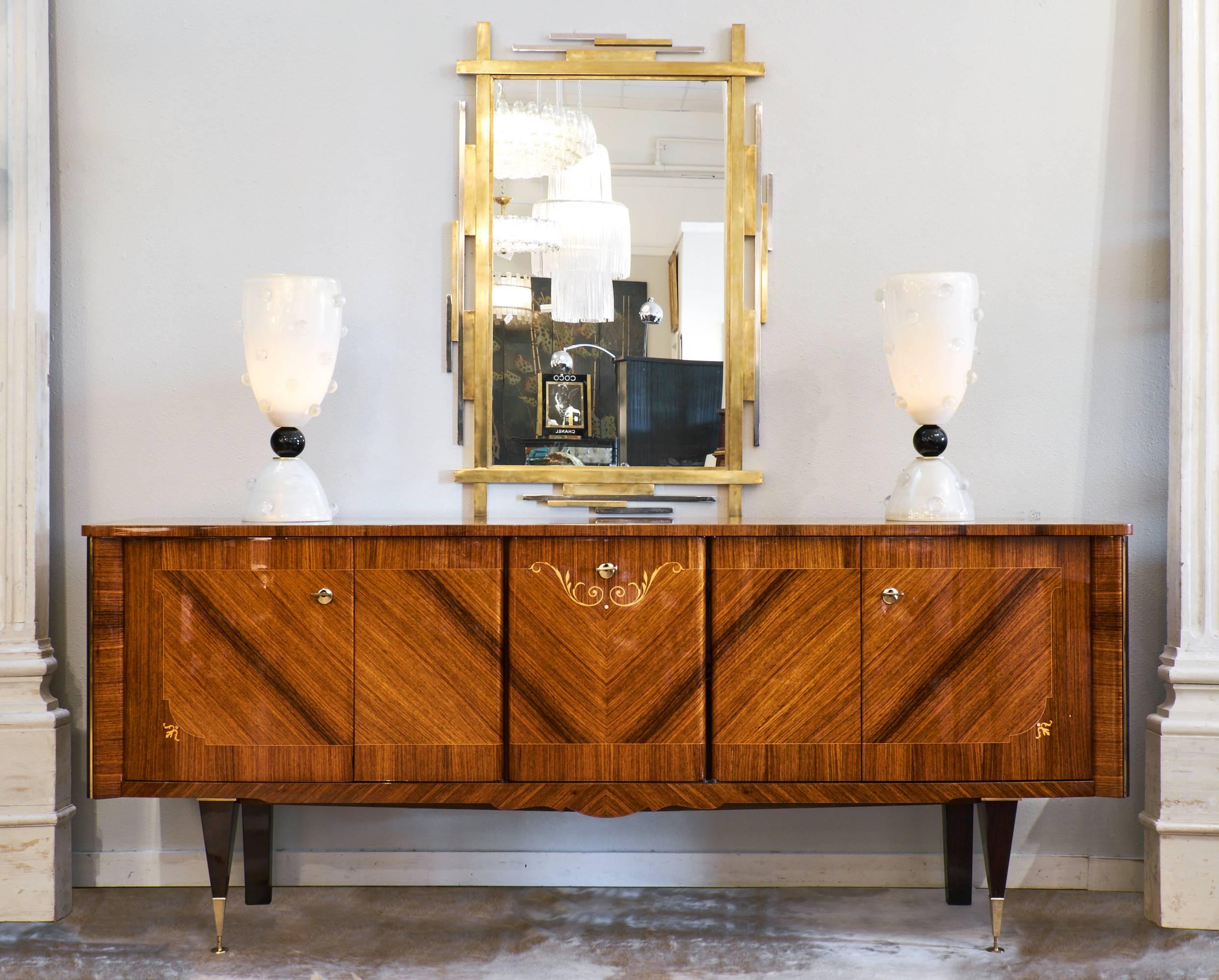 French Mid-Century Modern period credenza or buffet with a high polish rosewood exterior and lemonwood inlay, accented by ebonized and brass details and feet. Five doors open to reveal a lemon wood interior with adjustable shelves (both wood and