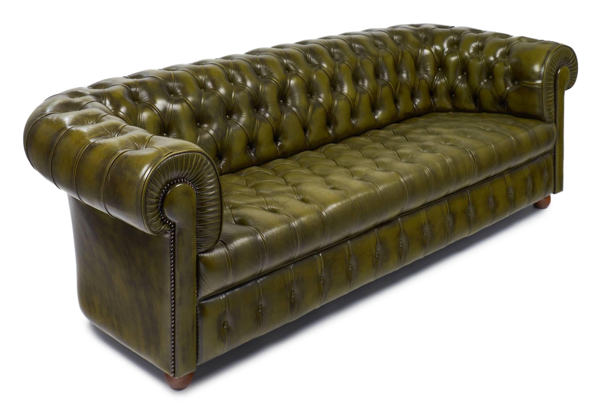 English vintage Chesterfield sofa in a beautiful green, tufted leather with brass tacks, rolled arms, and round wooden feet. This sofa is very comfortable. Ask us for information about the two matching armchairs. 