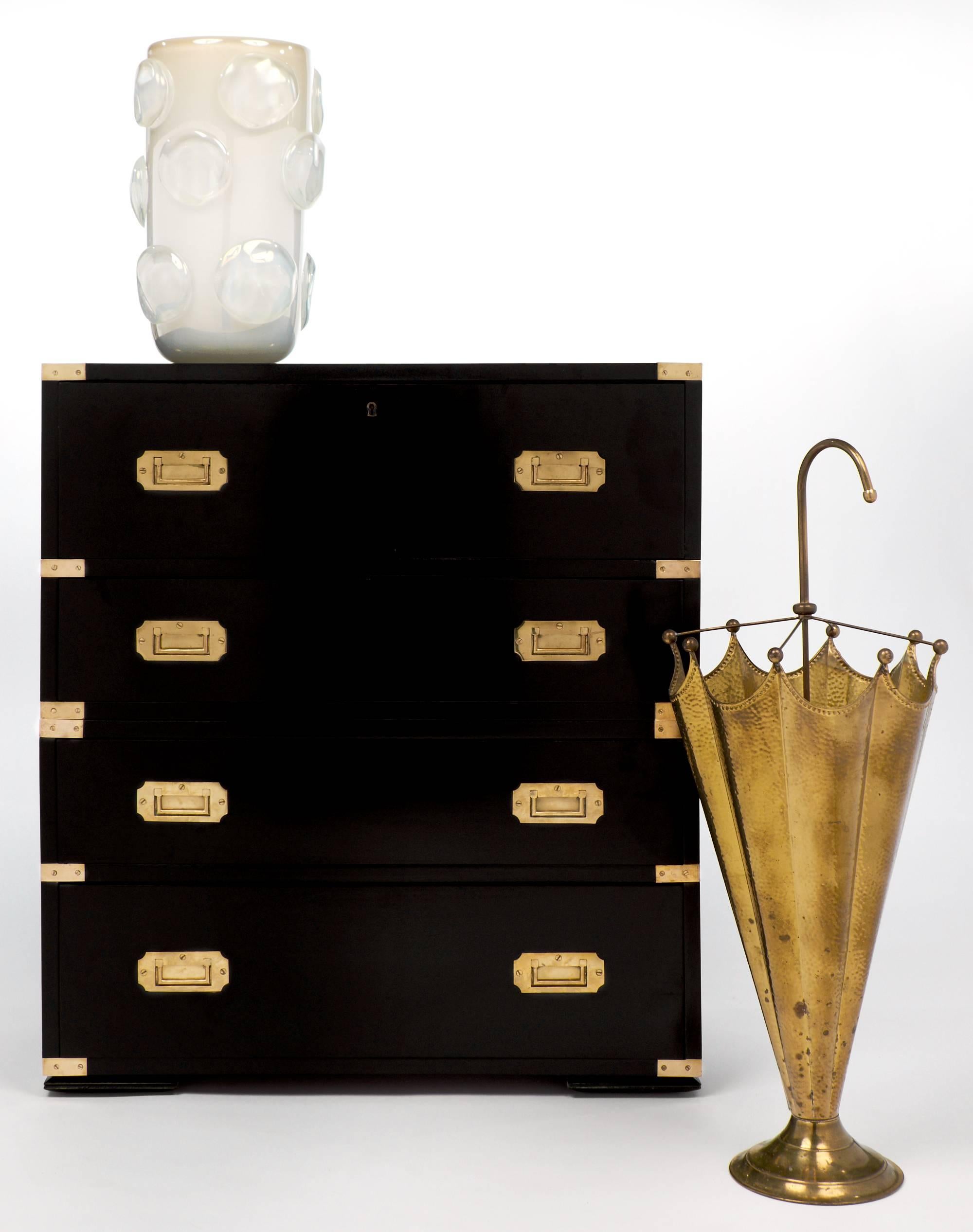Vintage campaign style chest with the iconic brass corners and inset handles, this piece also separates at the middle for easy travel. The top drawer front drops down as a leather writing surface, embossed with a gold leaf frieze, with several