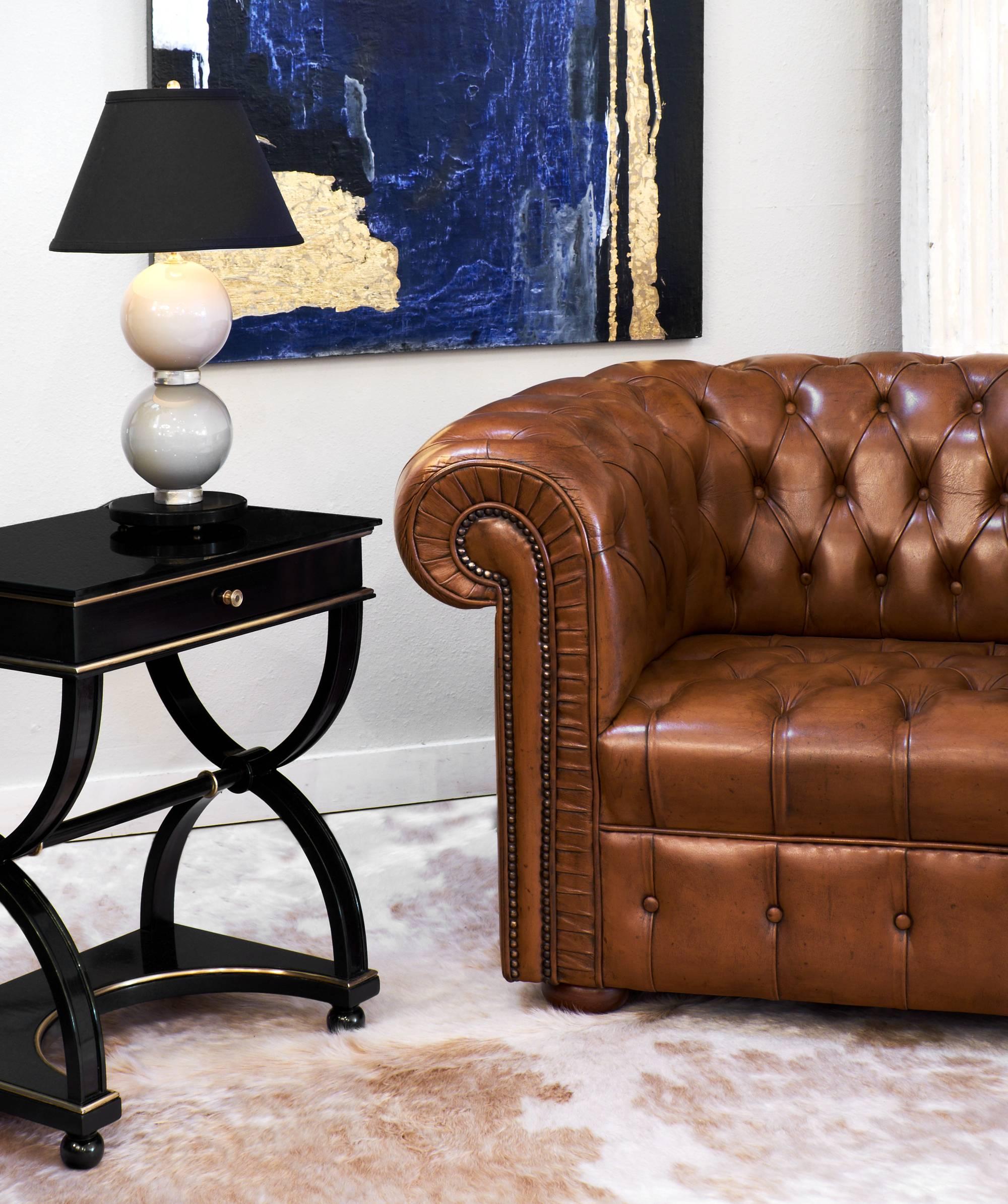 Chesterfield club chairs with tufted cognac leather upholstery and cherrywood bun feet. The rich color and rolled arms make these chairs Classic in style and so comfortable.