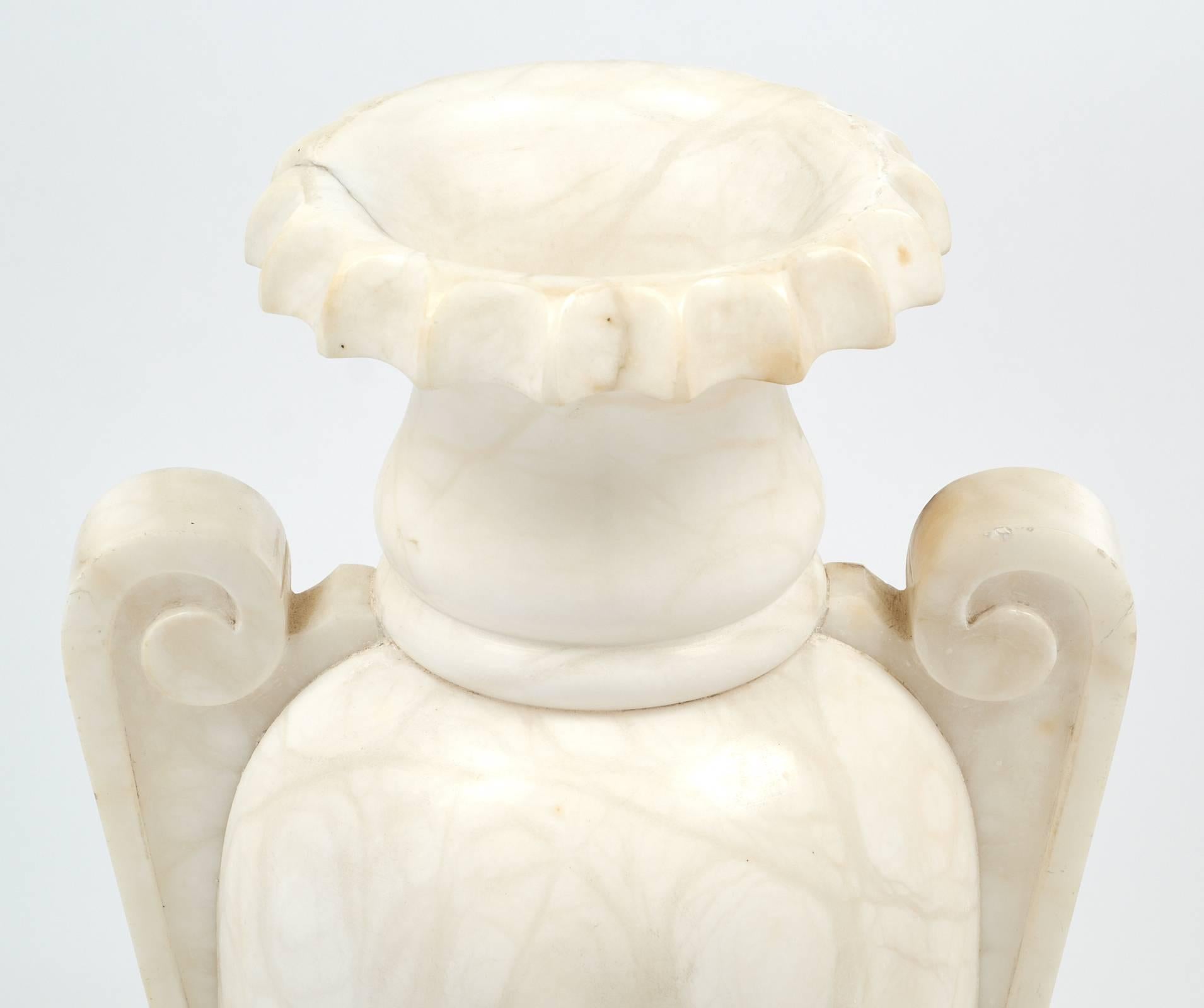 This classic alabaster urn lamp featured carved scroll handles and striking veining, circa 1930. When lit, this piece glows from within and brings warmth to the space. This unique lamp has been rewired for the US.