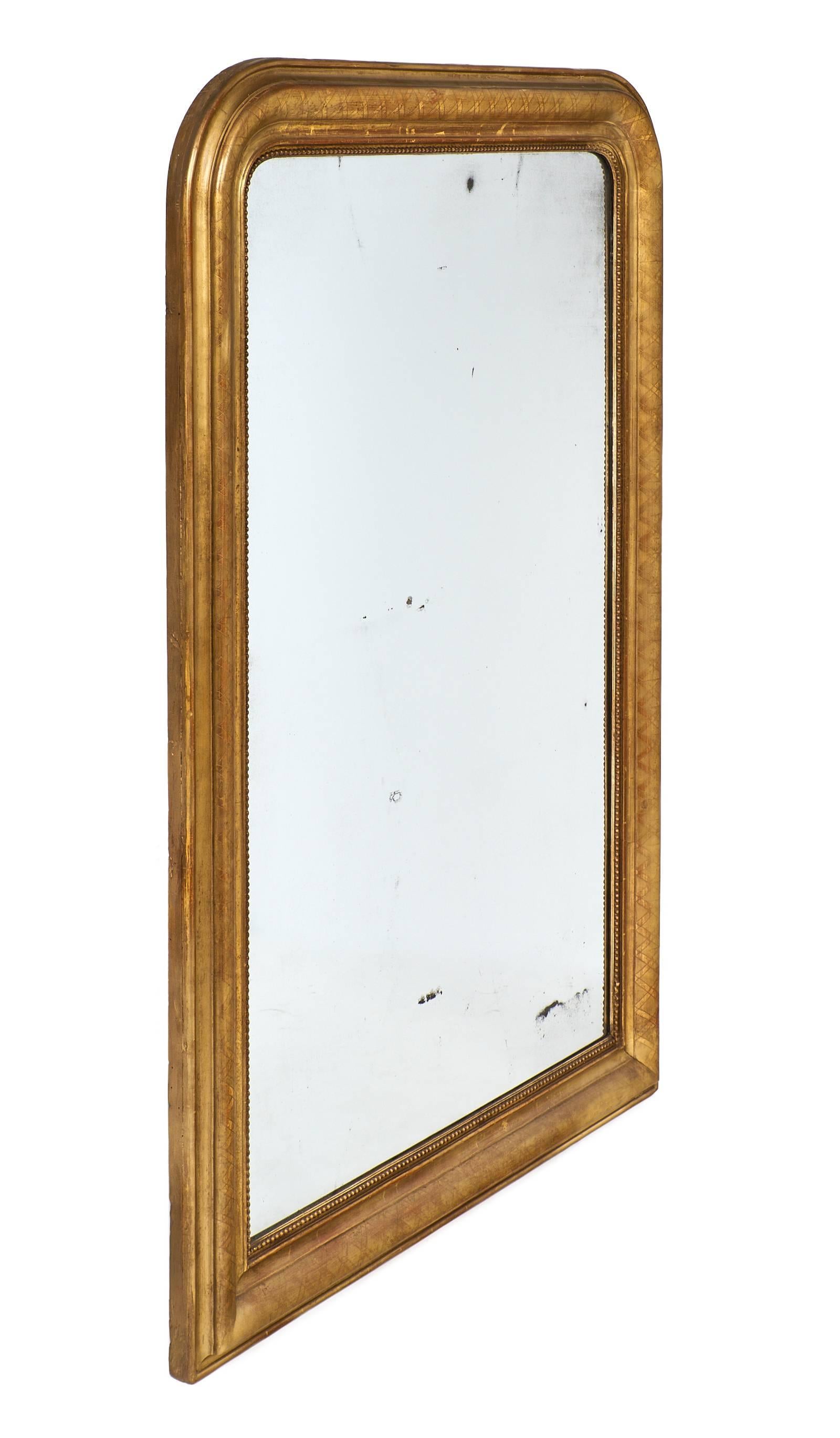 23 carats gold leaf mirror of the Louis Philippe period in France, circa 1845. This stunning piece is very large and has a lovely antique mercury mirror. The frame features geometric details in the gold leaf and a sienna glaze colored undertone.