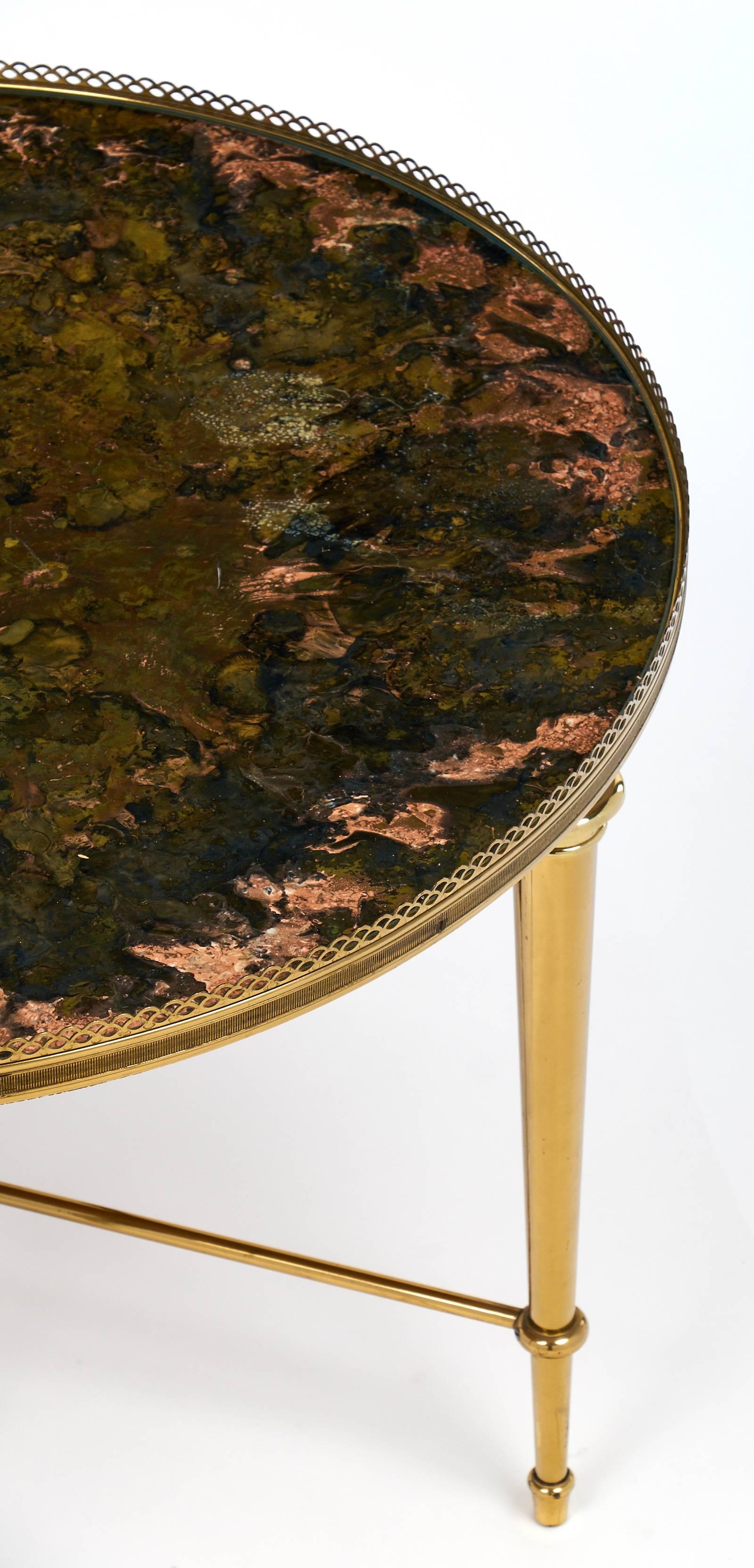 High quality solid brass vintage side table with brass gallery by Maison Ramsay. This table has tapered brass legs and a beautiful warm finish. We love the gold leaf in reverse finish on the glass top. The artistic acid work on the gold leafing