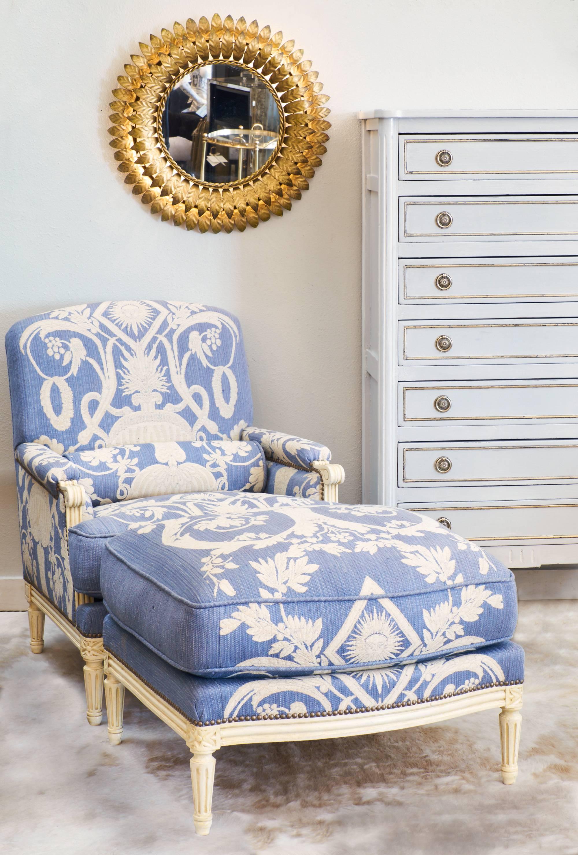 Louis XVI style bergère with stunning, original upholstery in a cornflower blue color with ivory colored embroidery. The wood frame is carved with floral details and fluted, tapered legs. This is a very unique and lovely piece that stands out in a