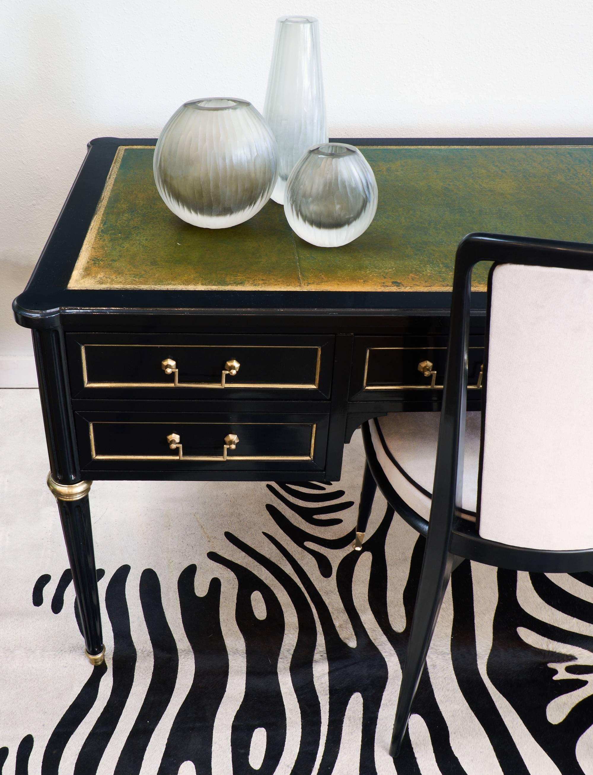 French desk in the Louis XVI style with a green gilt embossed leather writing top and brass hardware, trim, and feet. This piece has a pull-out leaf on each side to expand the length of the work surface. Five dovetailed drawers and tapered, fluted