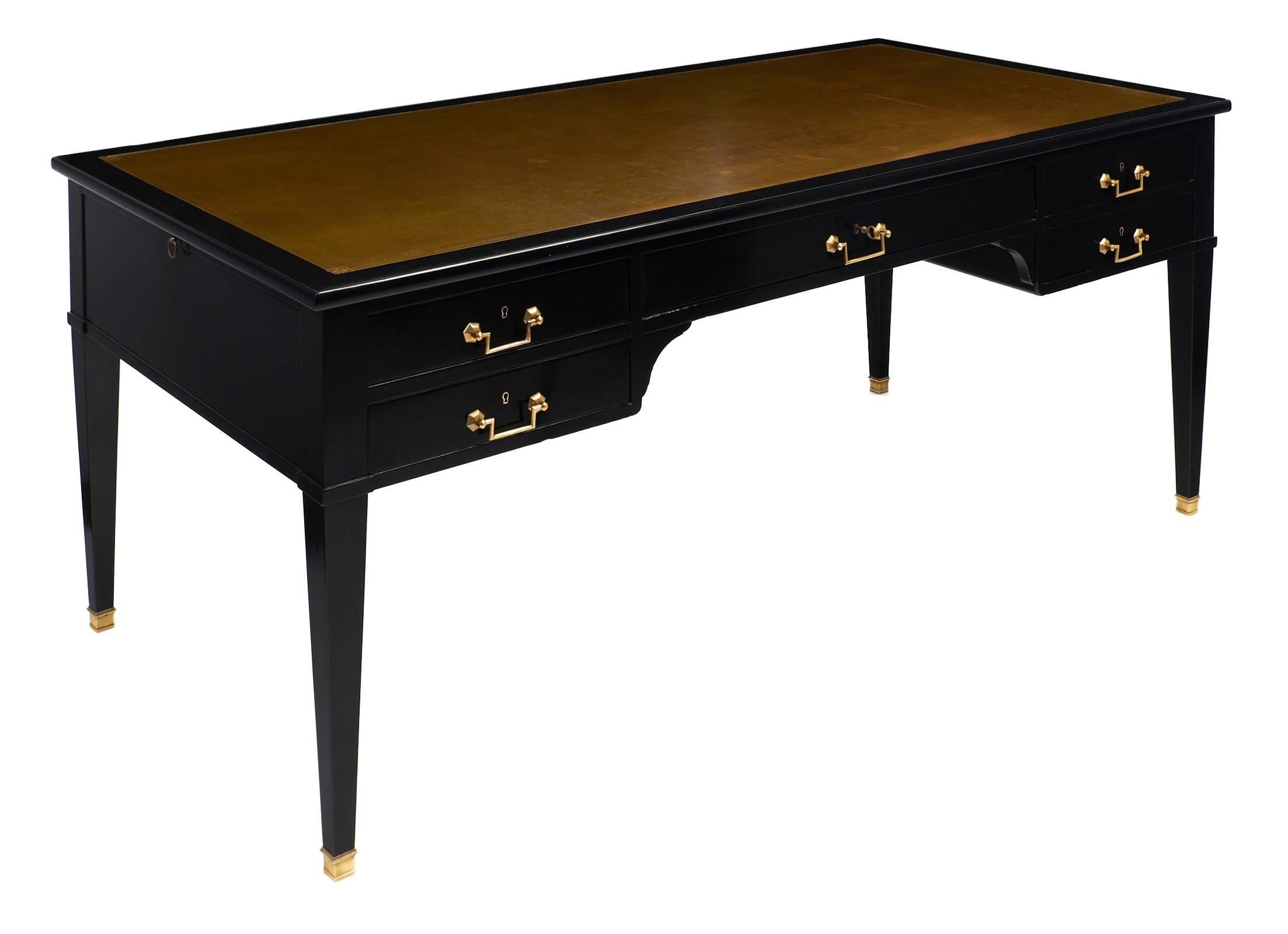 French Directoire style ebonized desk with a French polish finish and bronze colored leather writing surface. The desk has four tapered legs with gilt brass capped feet and five dovetailed drawers with original brass hardware. The top of the piece