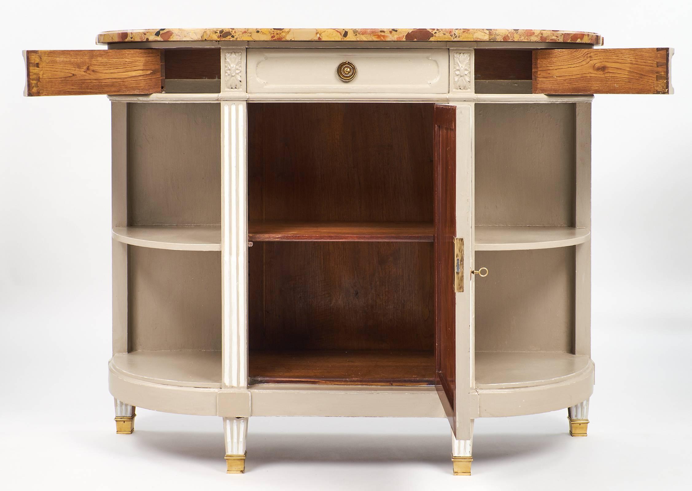 Louis XVI style French antique buffet with taupe grey painted finish and white painted details. The edges of the buffet are rounded, giving it a lengthened demilune shape. The brass hardware accompanies the three dovetailed drawers. In the center is