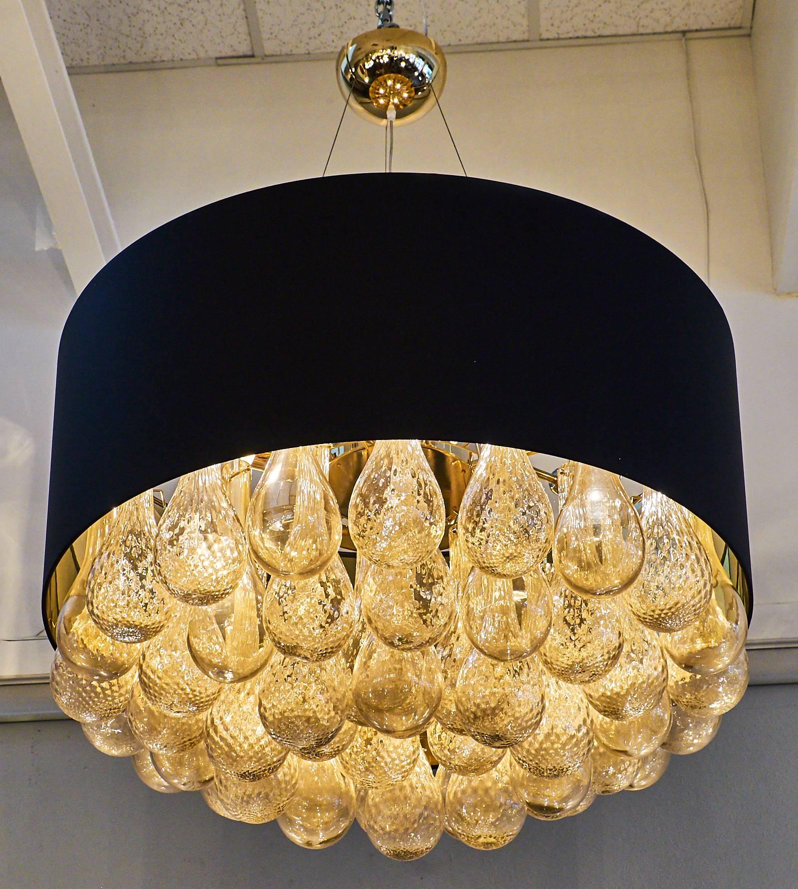 Dramatic black drum shade surrounding stunning gold “avventurina” Murano blown glass fused with 24-carats gold leaf. The glass drops differ between smooth and textured finishes. The light radiates off of the glass drops in lovely ways and the dark