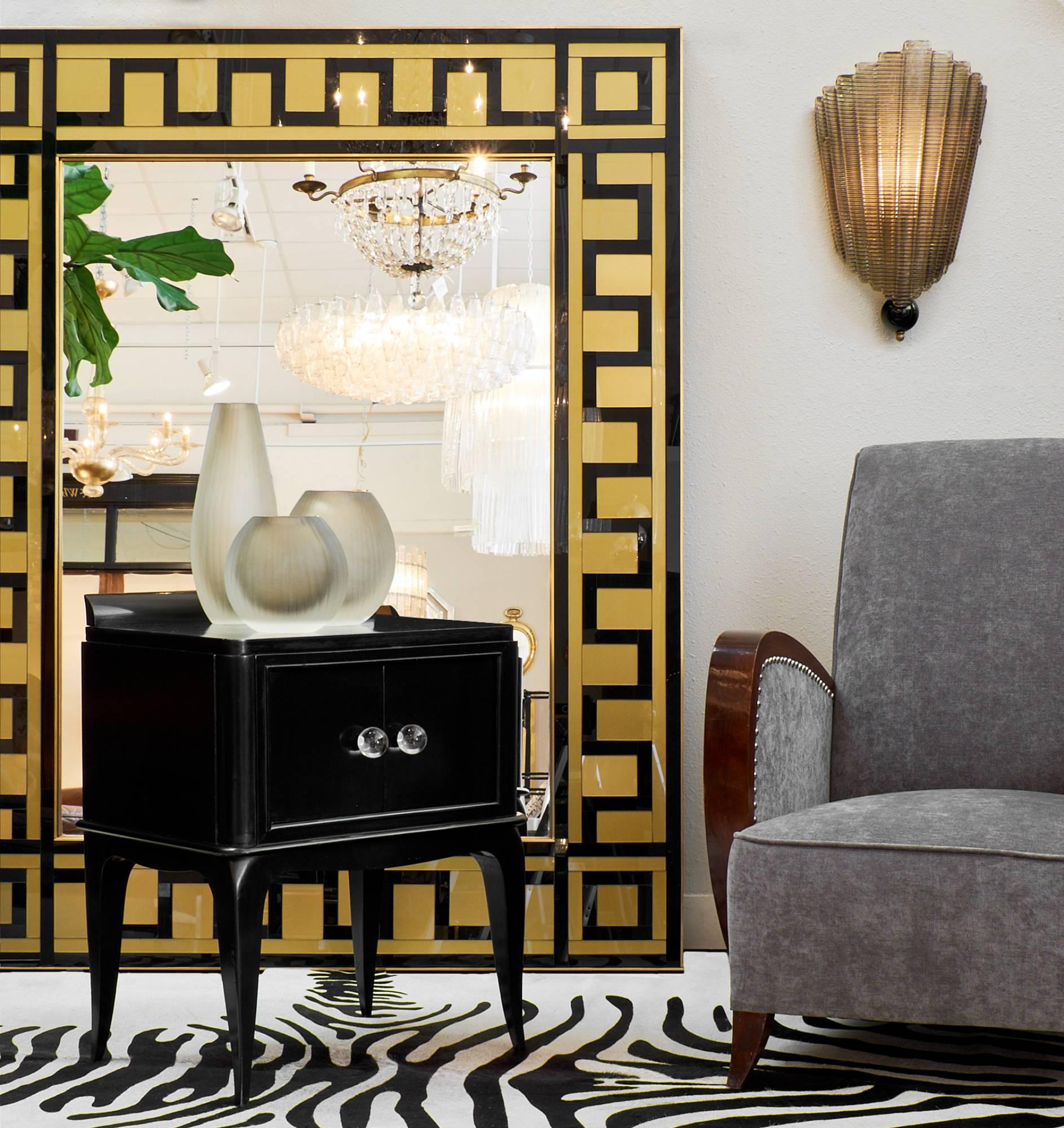 Art Deco style side tables in the charming manner of André Arbus. Made of ebonized maple and finished with a lustrous French polish, these tables have spherical, clear Murano glass knobs to embellish these elegant cabinets. We love the typical twist