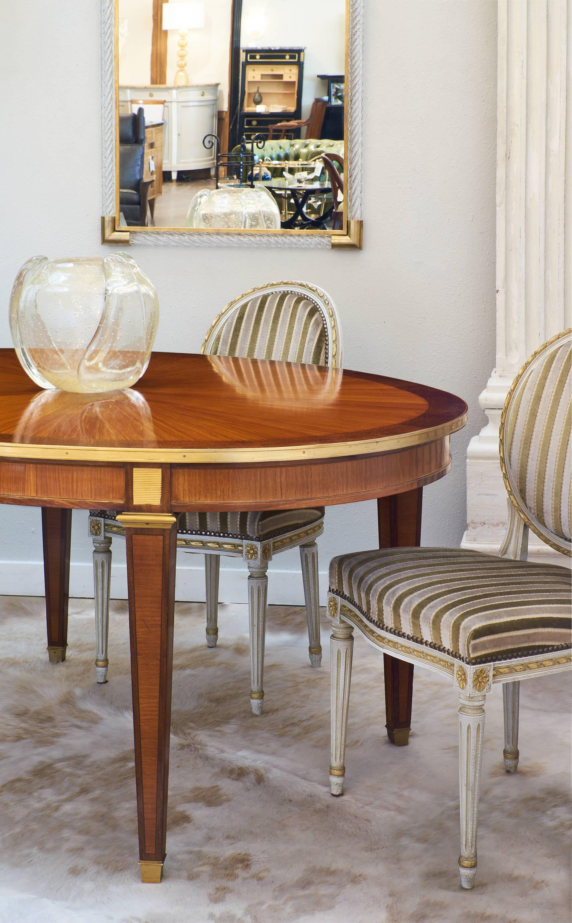 Superb French Louis XVI style oval dining table, circa 1900. This beautiful piece is made of rosewood and has tinted rosewood marquetry and parquetry. This piece features bronze on the feet, moldings, and trim. The legs are tapered. High quality