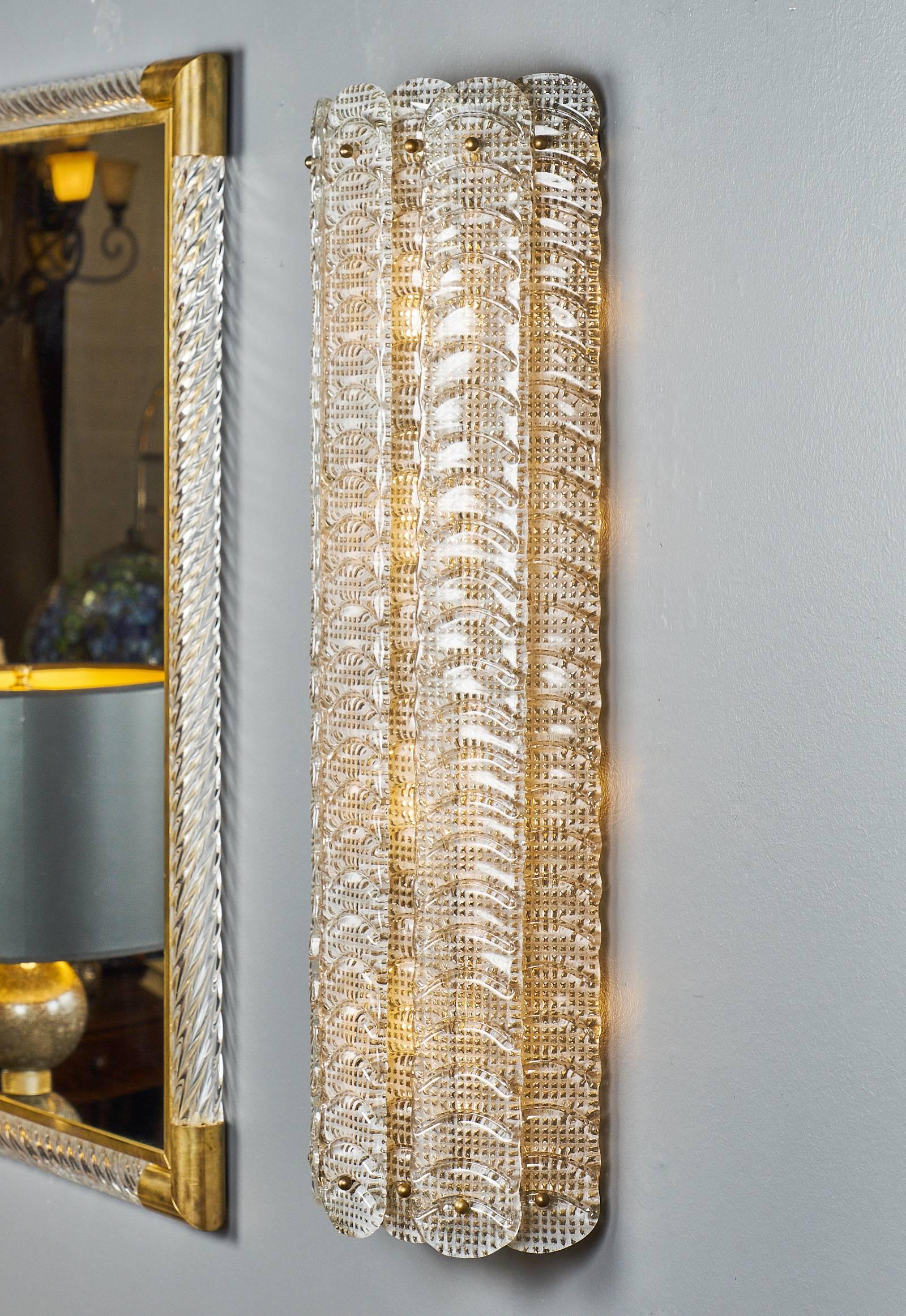 Pair of handblown Murano glass wall sconces, each featuring eight stamped blades with “Reticello” weaving and stylized feather-like texture. The effect makes these fixtures look like python skin! The sconces provide great warm, diffused light. Each