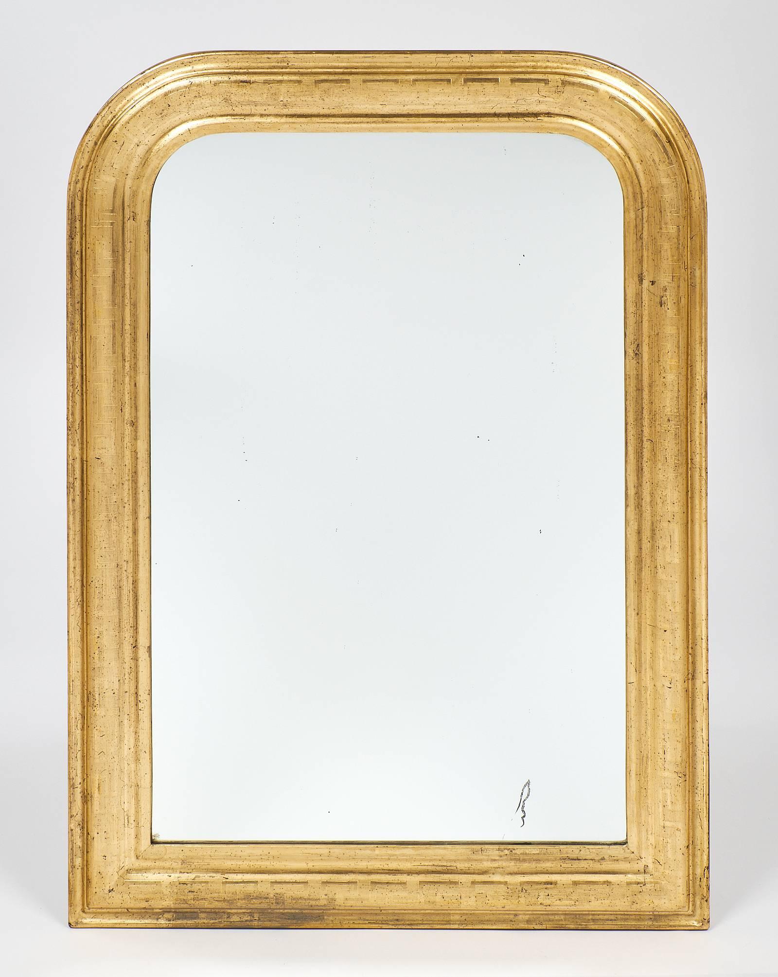 Pair of antique Louis Philippe mirrors with a 23-Carat gold leafing on a sienna glaze. This pair is chiselled with a Greek key frieze. The mirrors are original.
