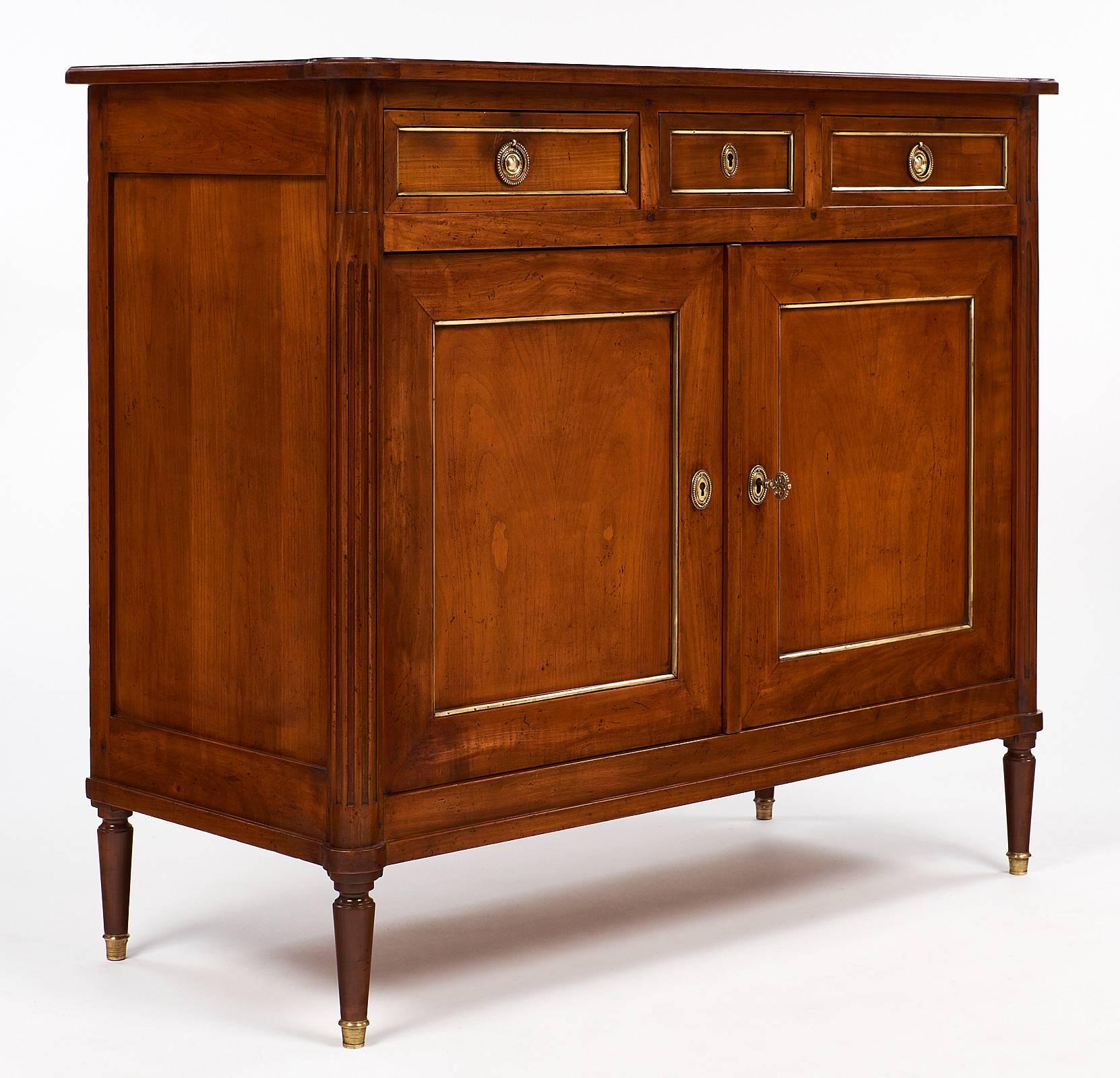 Beautiful antique buffet made of solid cherrywood and featuring finely cast bronze hardware and feet, gilt brass trim, two doors, and three drawers. This piece has a beautiful honey toned patina to the fruitwood! We love the high quality Provincial