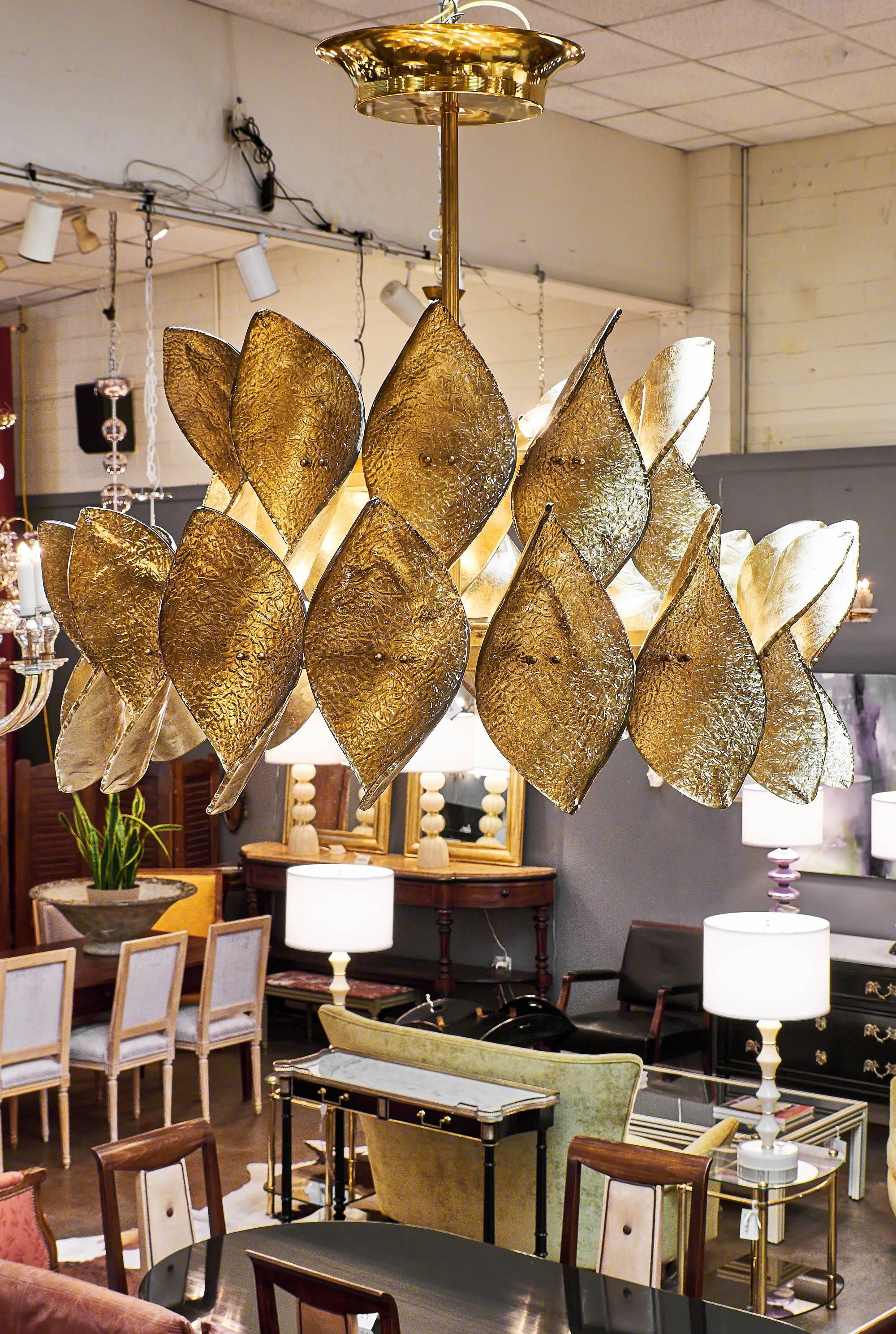 Dynamic Italian modernist chandelier from the island of Murano. The brass structure sustains on two levels an array of glass leaves fused with 23-carat gold leafing. The thick leaves are expertly crafted and textured while still in fusion to provide