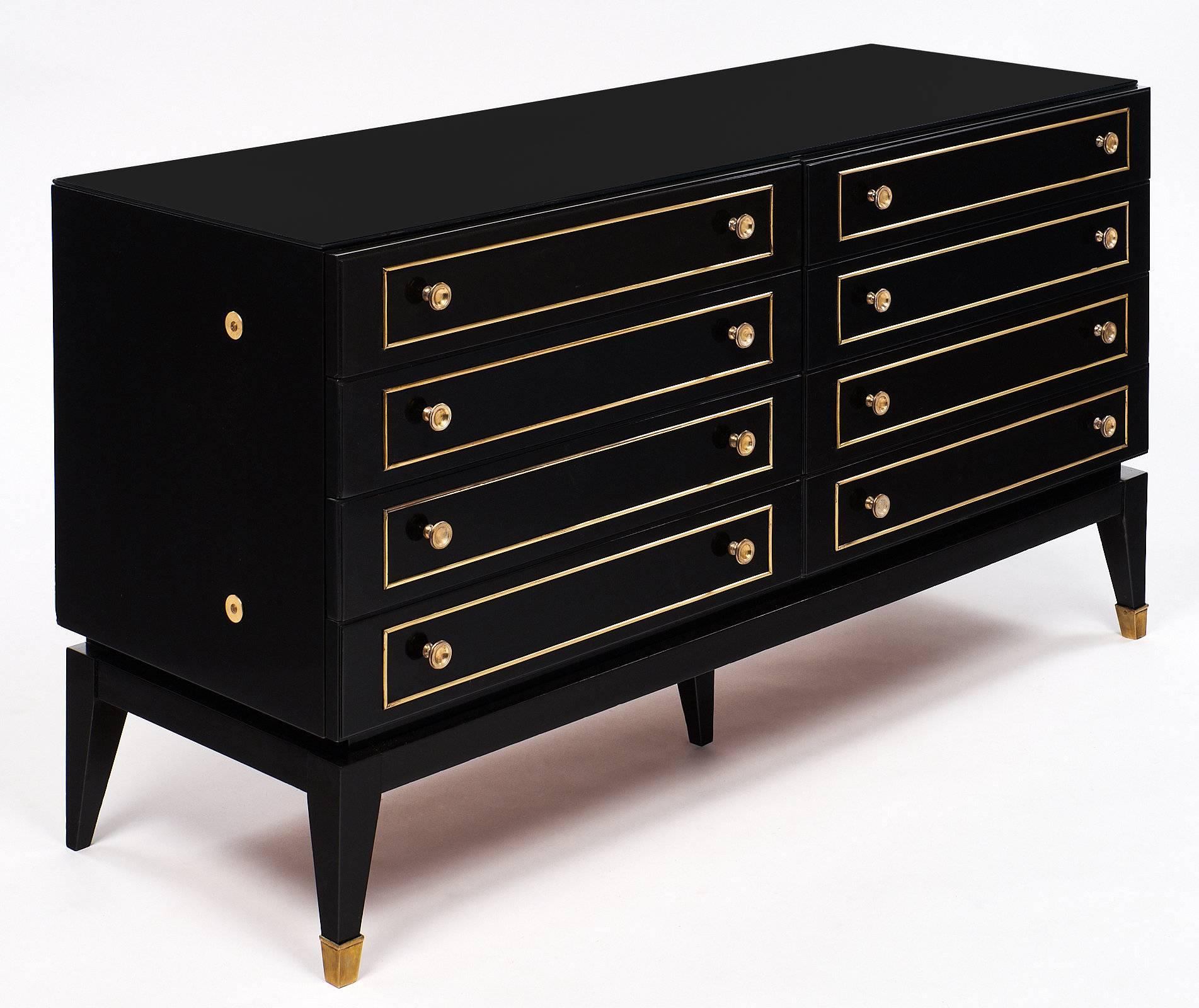 Wonderful chest of drawer made of cherrywood and featuring brass trims throughout, brass knobs, and eight drawers. This piece is ebonized, topped with a black cobalt glass, and finished with a French polish. This is a classy, great piece with
