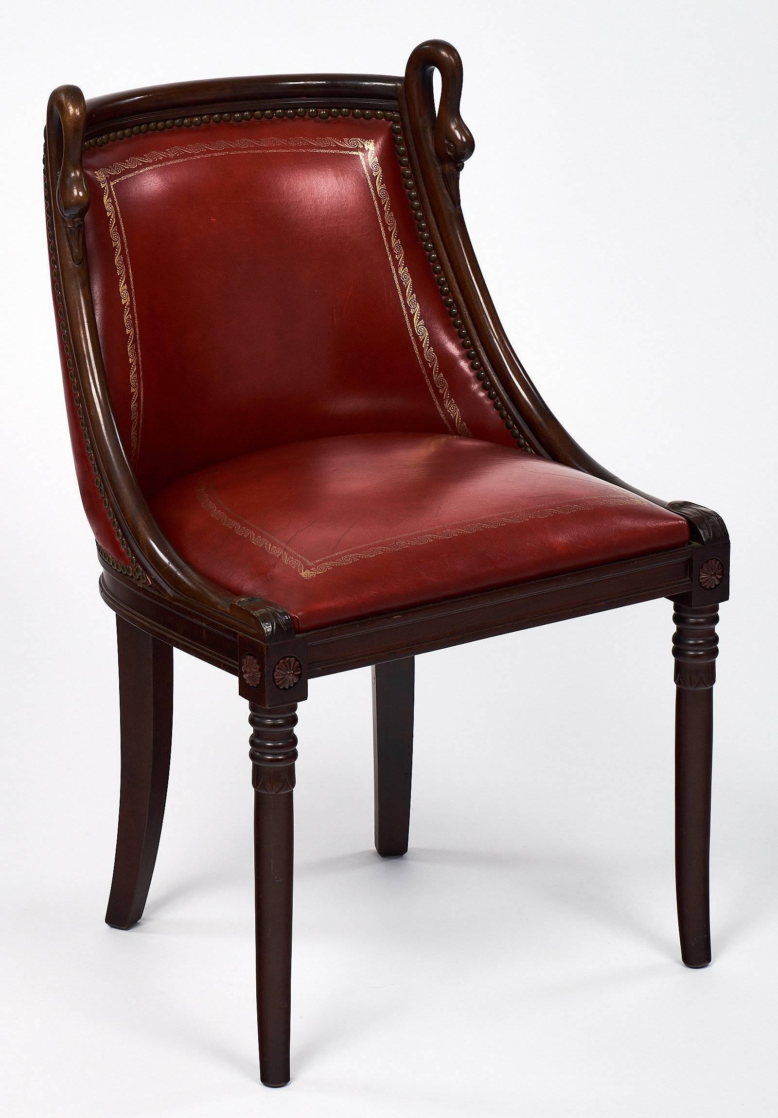 Empire style set of charming chairs made of mahogany and featuring hand-carved swan neck details on the barrel backs. These beautiful chairs have full grain crimson red leather with 23 carat leaf embossing. This set have saber back legs and are very