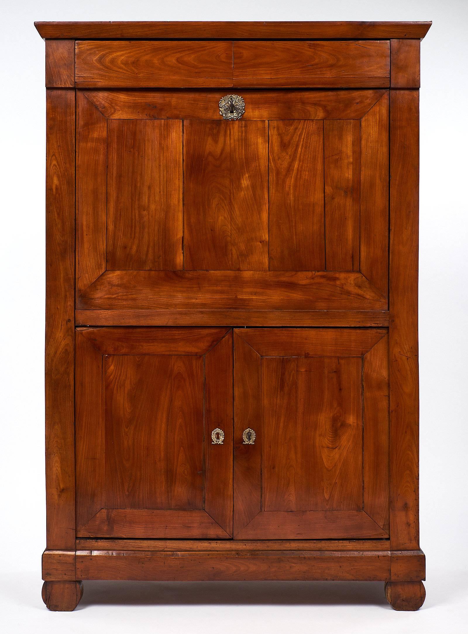 French antique secrétaire made of solid cherrywood, this piece has a Provincial Directoire drop front, a top dovetailed drawer, and two doors below. The interior features nicely curved shelving and five dovetailed drawers. The writing surface is